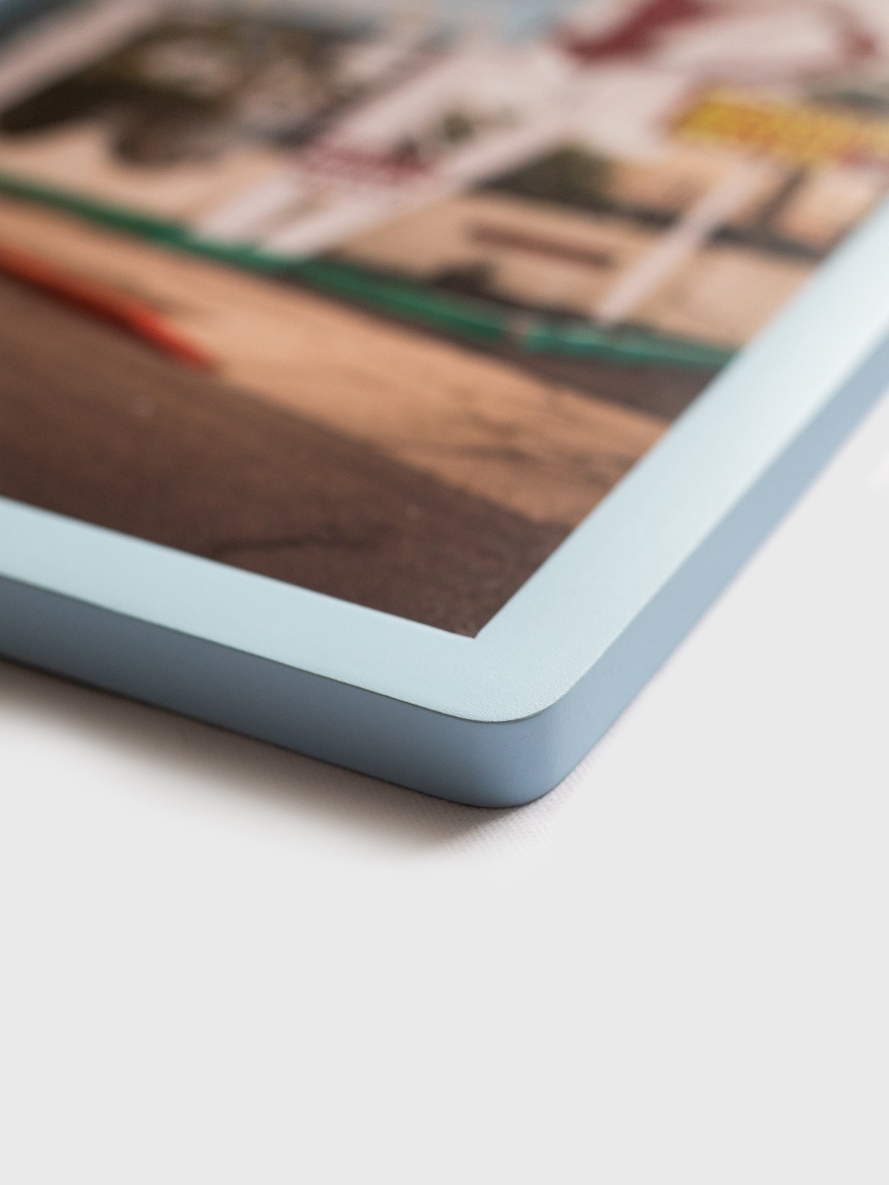 Close-up side view of a premium ice blue wood photo frame showing the smooth matte finish and glass corner detail on white background.