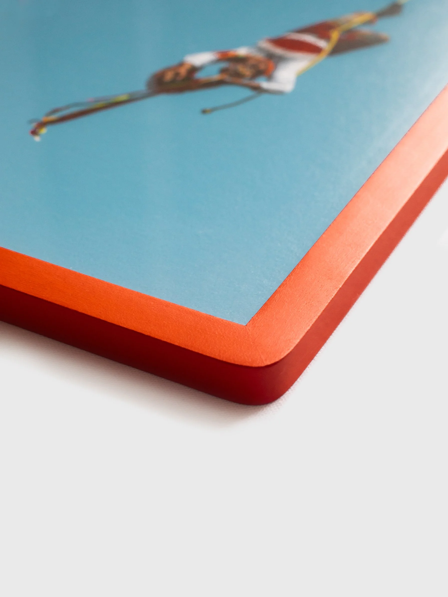 Close-up angled detail view of a handmade matte red wooden picture frame showcasing the smooth rounded corners and premium flush-fit edge.