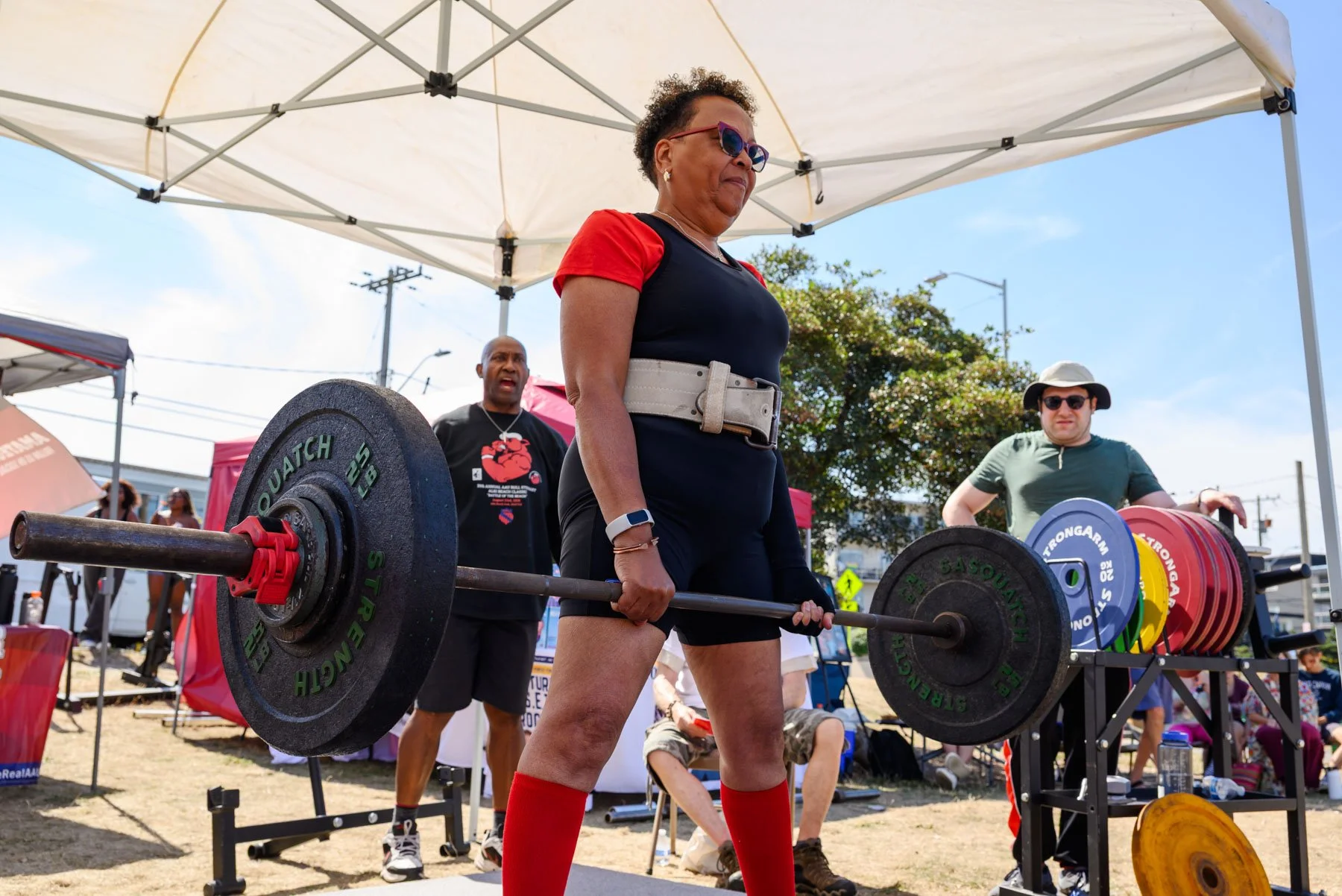 Older woman deadlifting heavy barbells outside