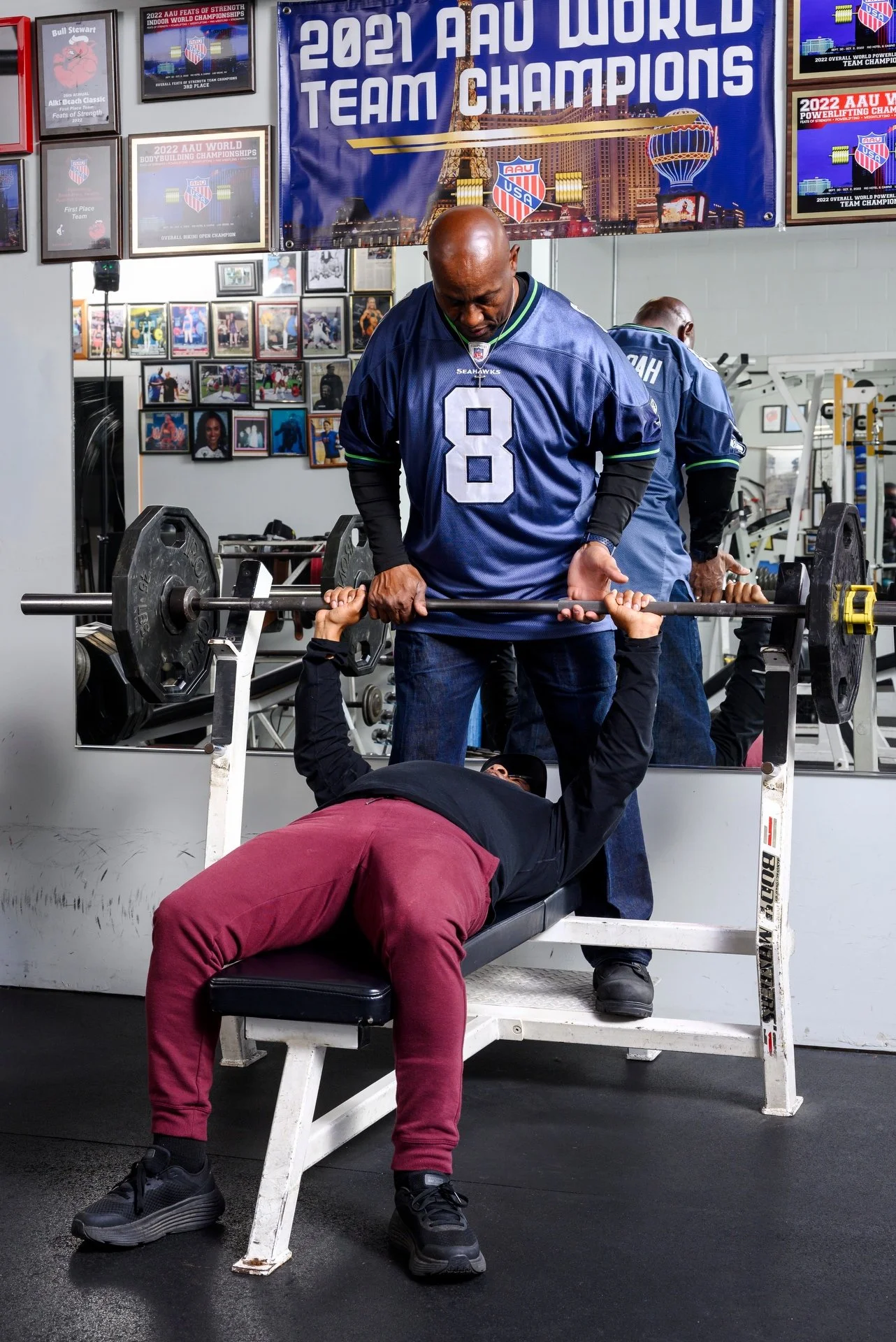 Bull Stewart spotting a man doing chest press with barbell and weights