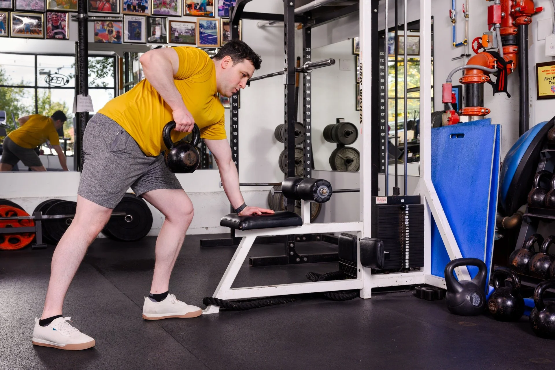 Man in yellow shirt doing kettlebell exercises
