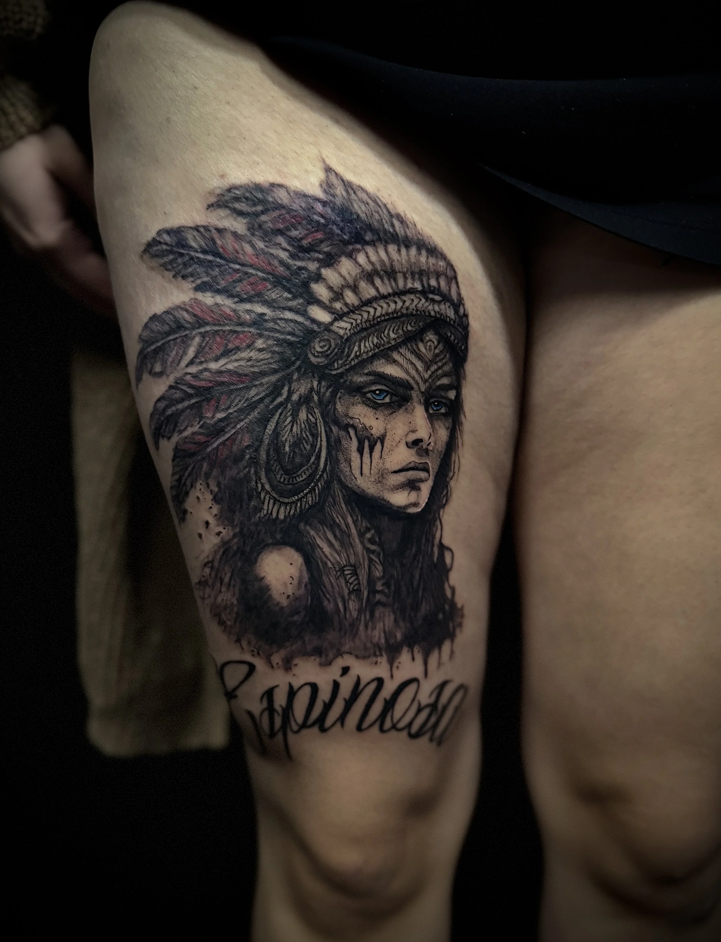 Tattoo of a Native American woman wearing a feathered headdress on upper arm.