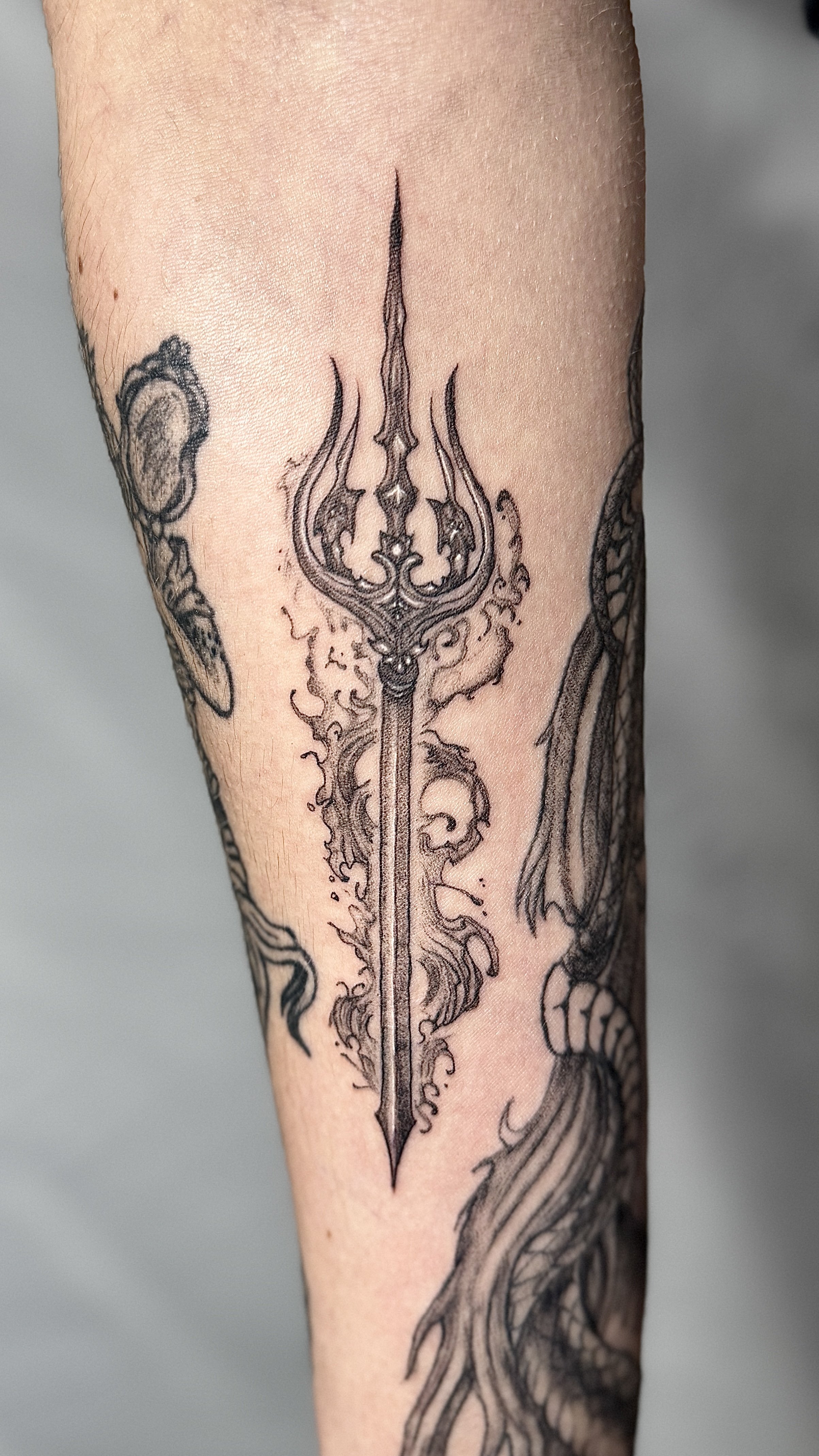 Tattoo of a detailed sword with flames on a person's arm.