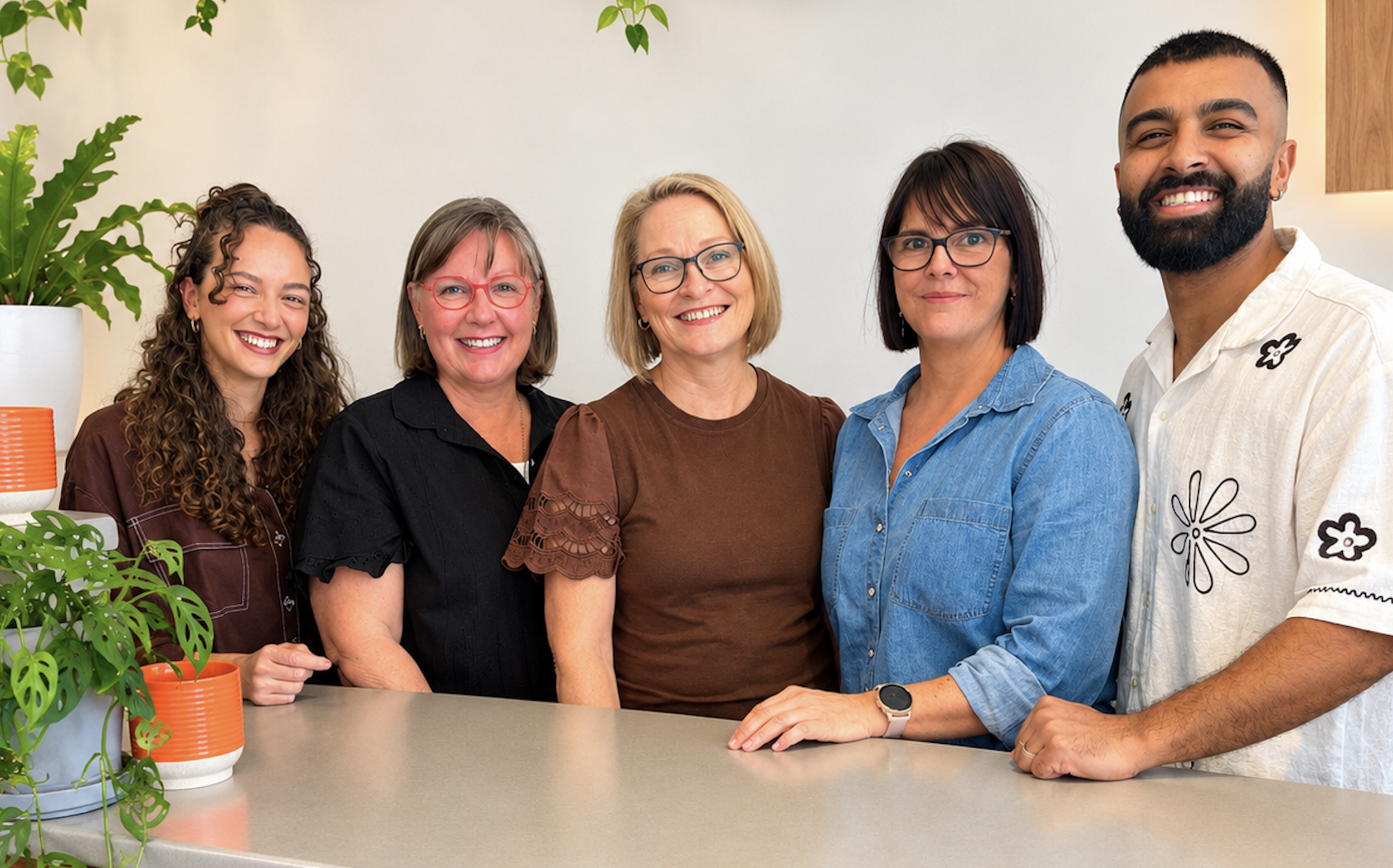 The friendly Vibrant Family Chiropractic team smiling together at the clinic reception desk.
