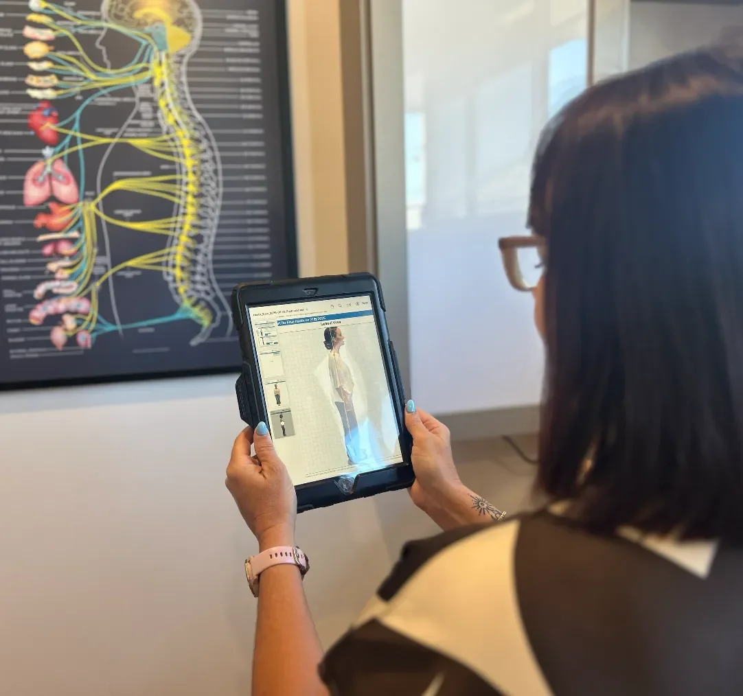 Chiropractor at Vibrant Family Chiropractic using digital technology on a tablet to assess posture and spinal alignment during neurostructural testing.