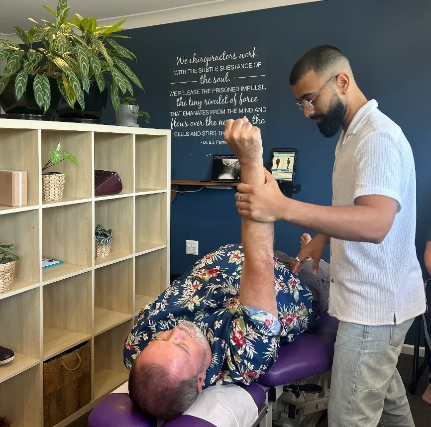 Chiropractor at Vibrant Family Chiropractic performing an assisted arm and shoulder stretch on a patient lying on a treatment table.
