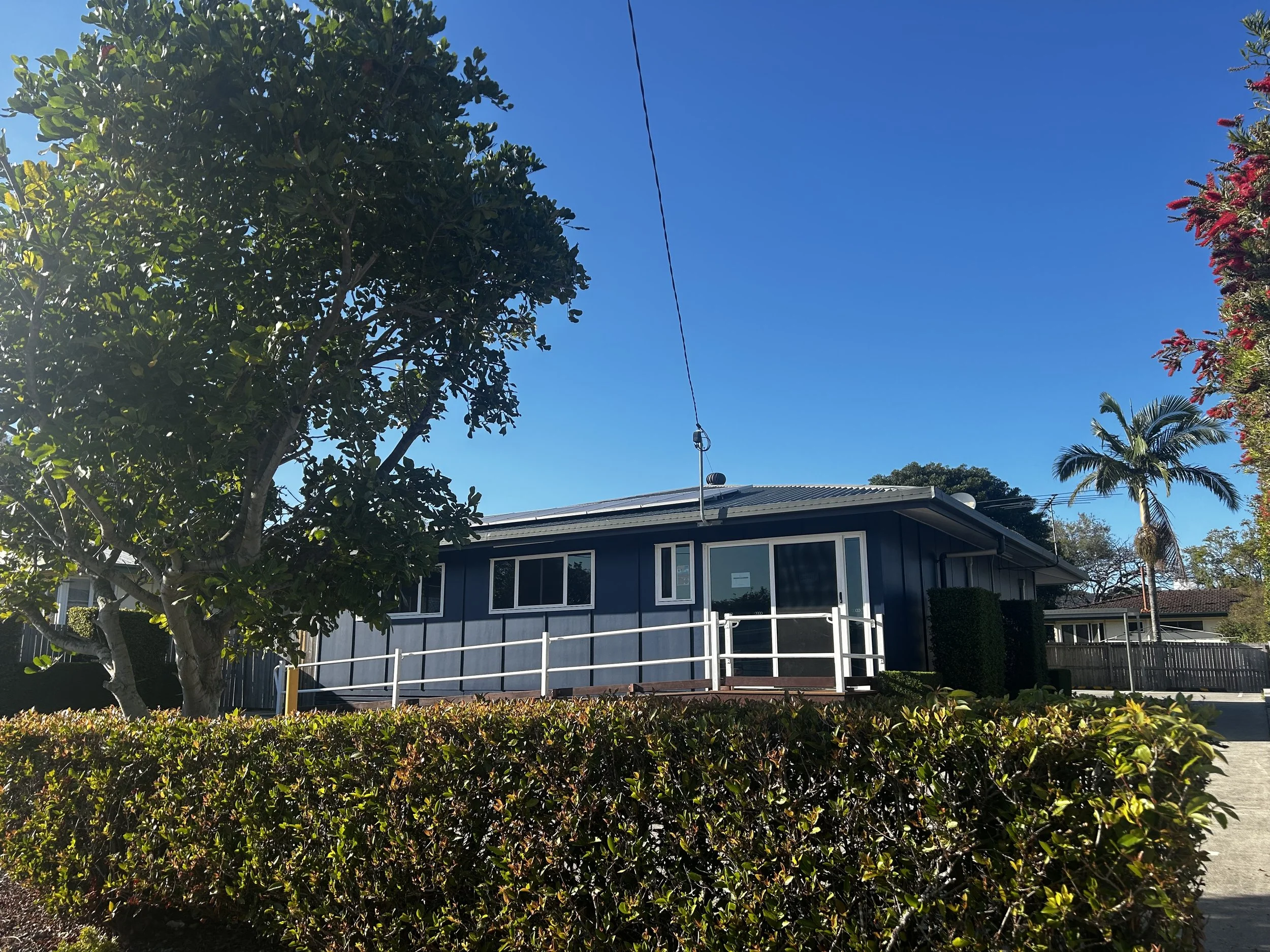 Image of the Vibrant Family Chiropractic building. Bright blue sky in the background with green luscious foliage.