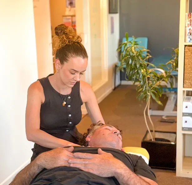 Chiropractor at Vibrant Family Chiropractic providing gentle neck treatment to a patient lying on a chiropractic table.