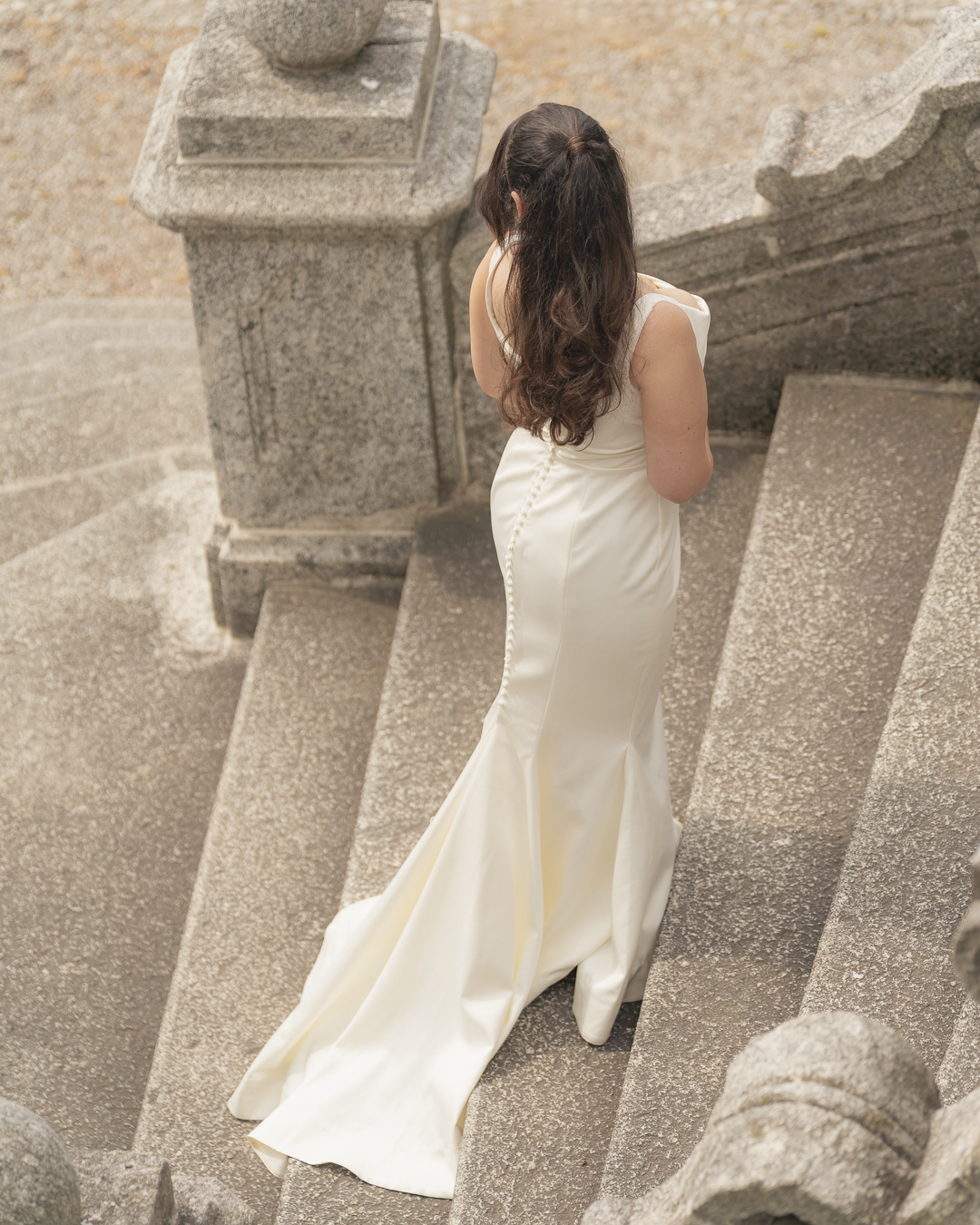 Donna in un abito da sposa che scende le scale di pietra, vista posteriore