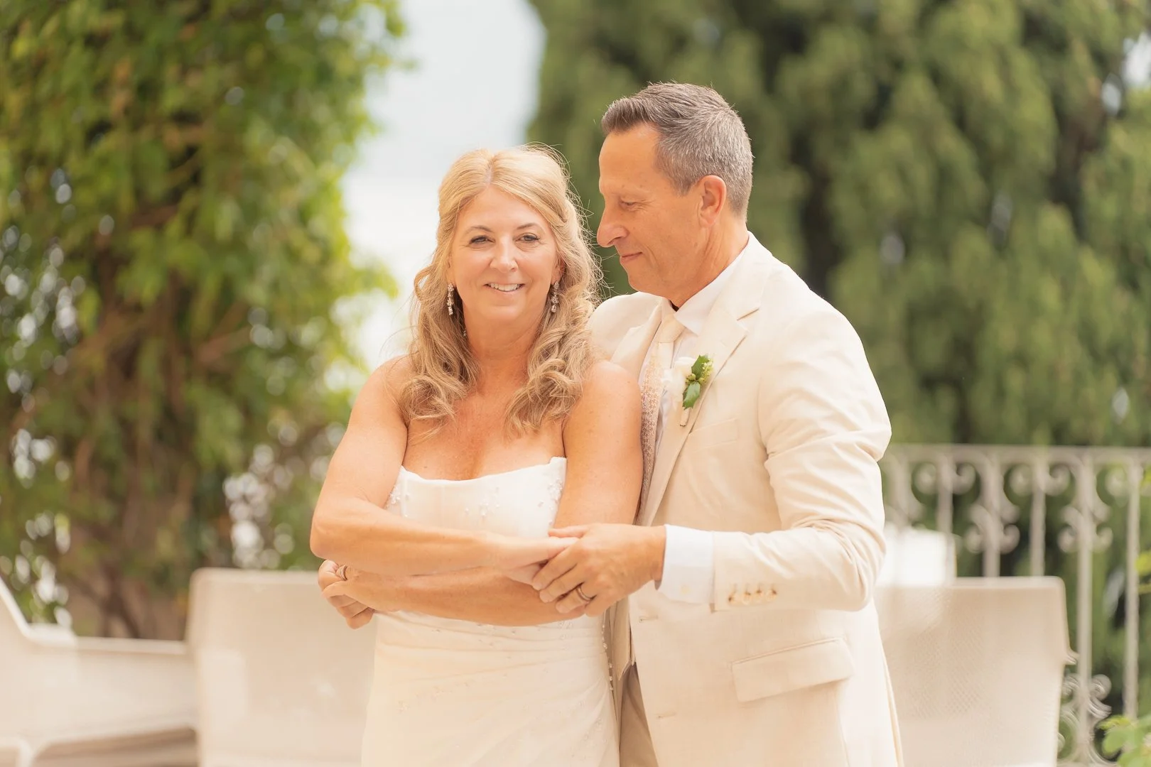 Coppia di sposi anziani che si abbracciano sorridenti in un matrimonio all'aperto.