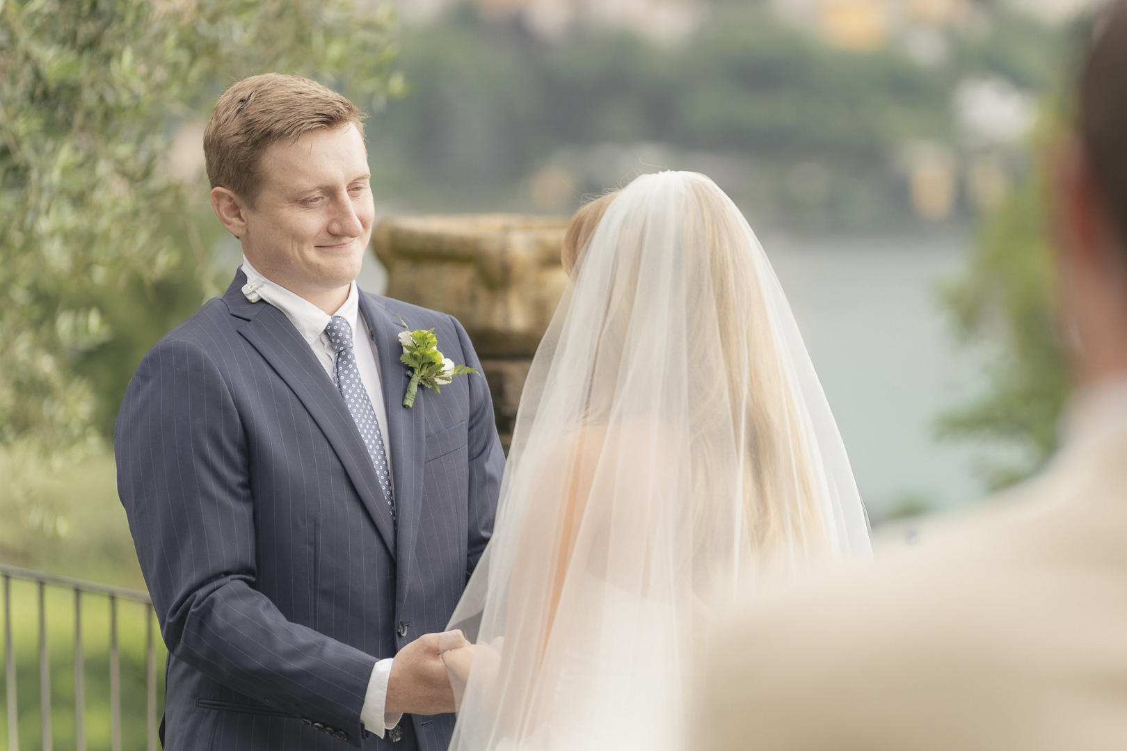 Sposi che si scambiano i voti di matrimonio in un ambiente all'aperto con acqua e natura sullo sfondo.