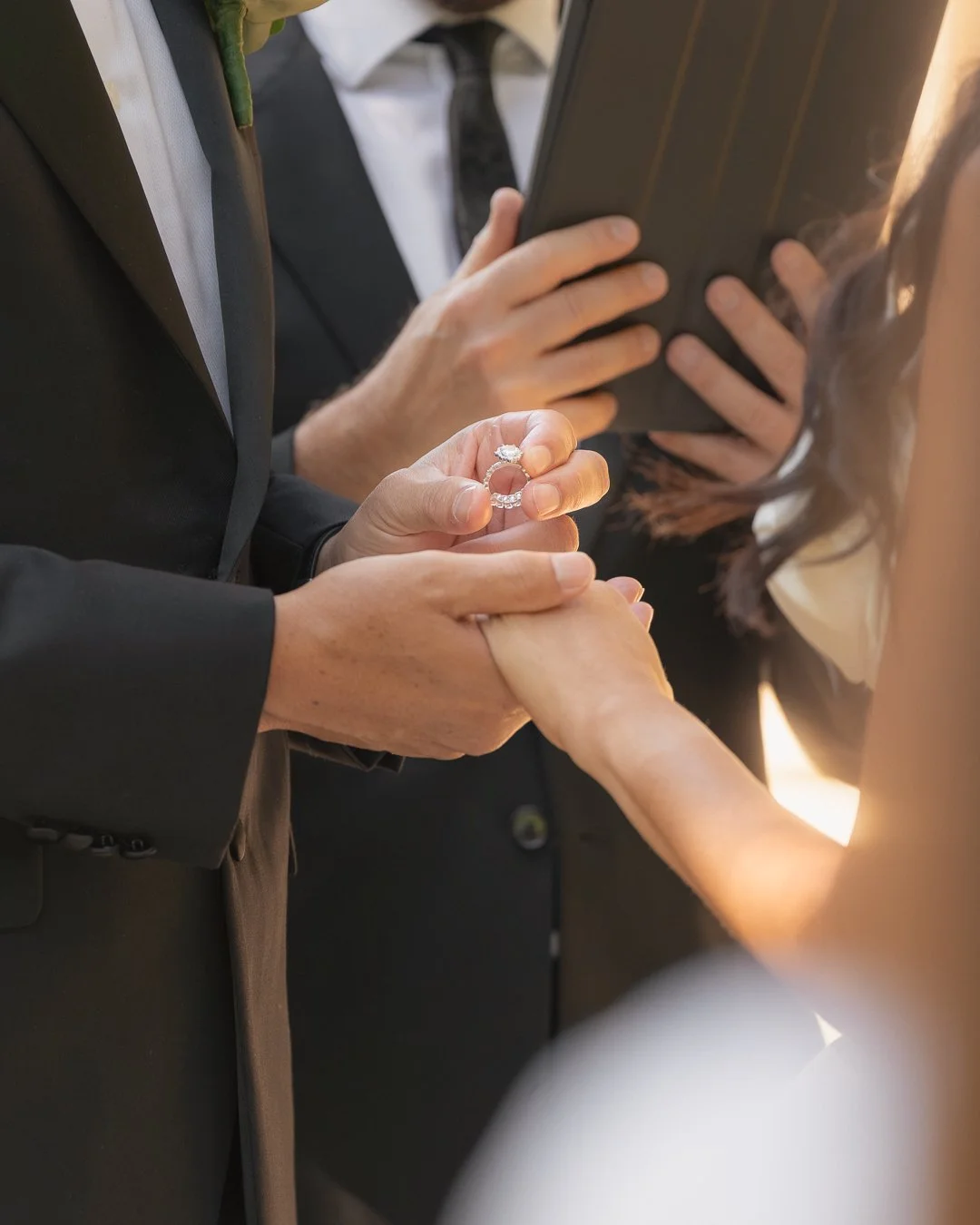 Un matrimonio sta scambiando gli anelli, una coppia si tiene per mano mentre il partner le mette l'anello sul dito.