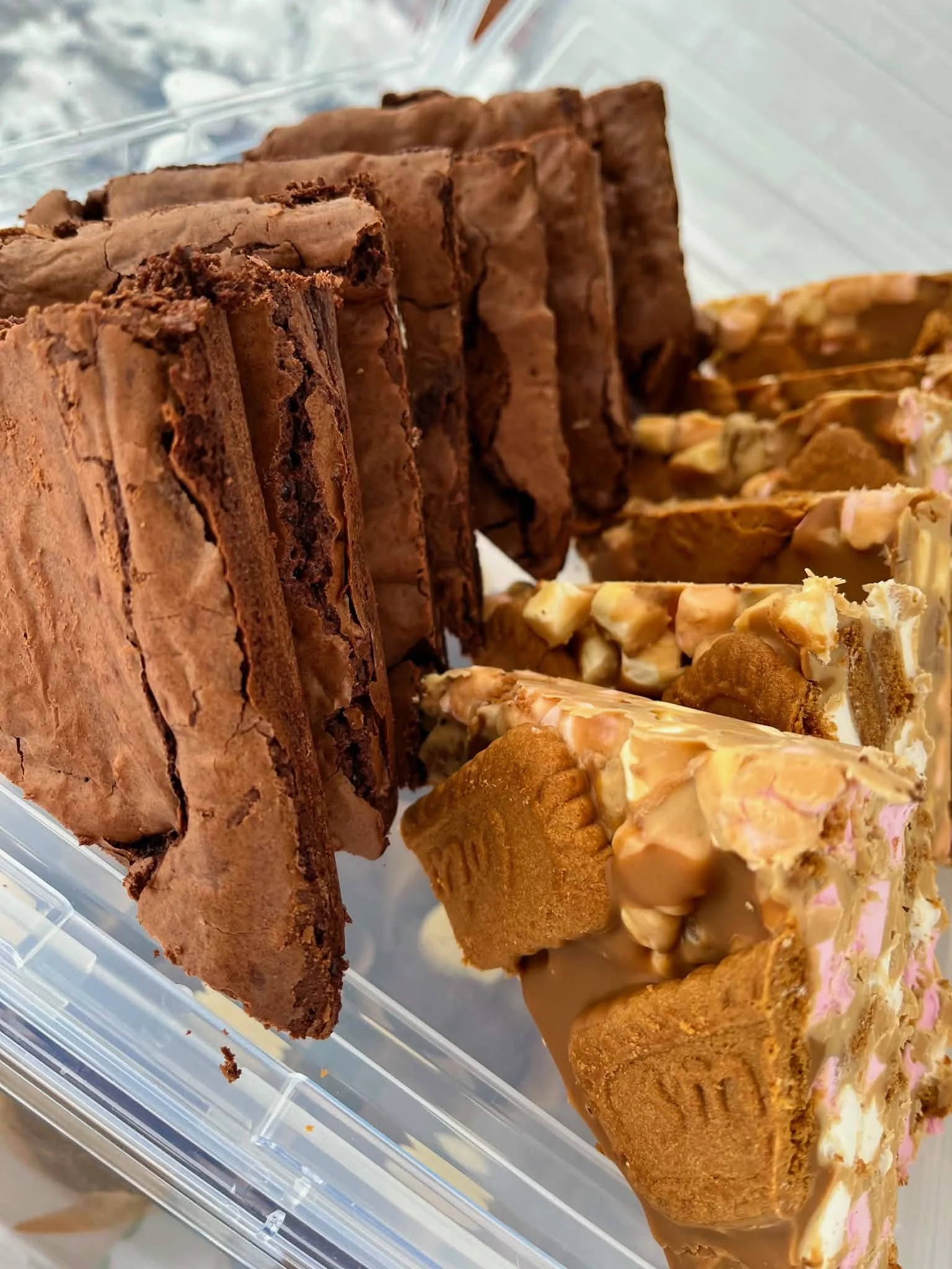 Assorted caramel and chocolate flavored fudge in a clear plastic container.