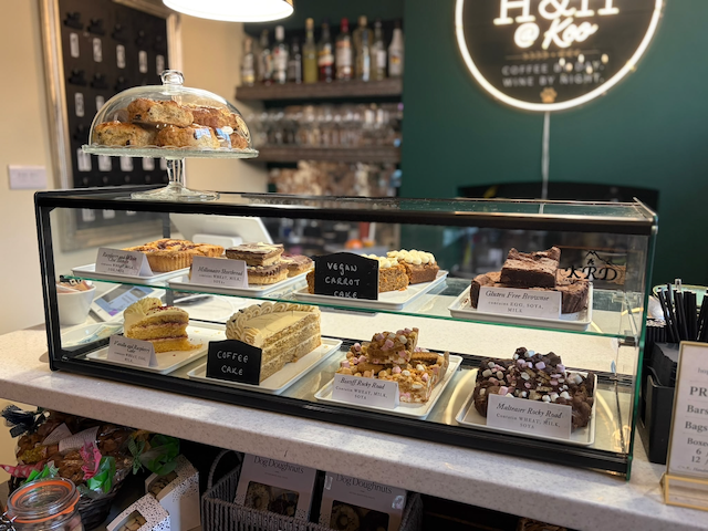 Bakery display case filled with assorted vegan cakes, brownies, pastries, and donuts at a cafe