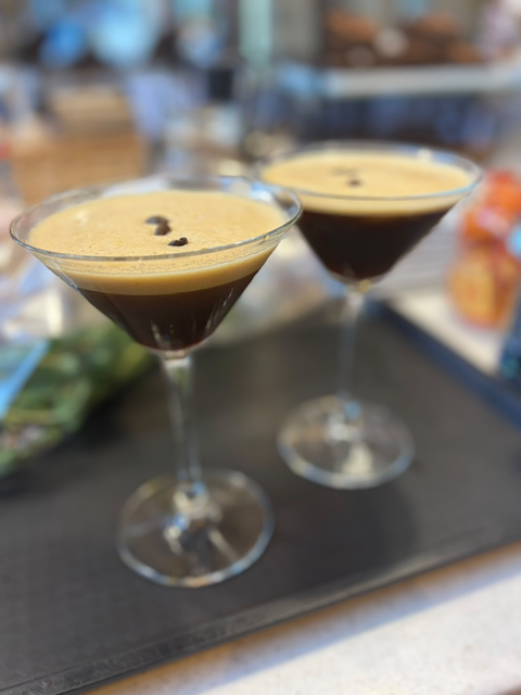 Two coffee martini cocktails in stemmed glasses on a bar counter