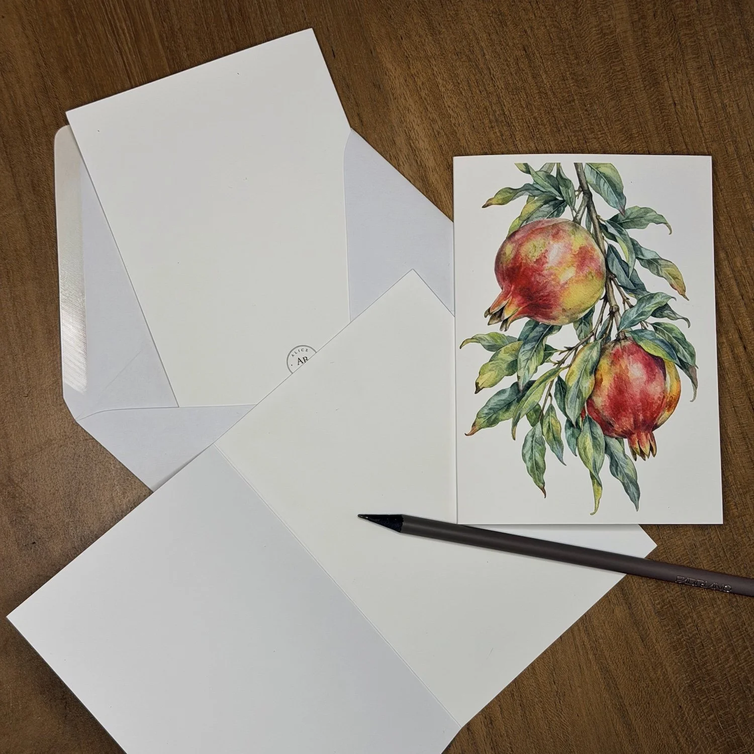 Watercolor greeting card featuring ripe red pomegranates and green leaves, illustrated in a detailed botanical style by Alice Botanica. Copia descrizione