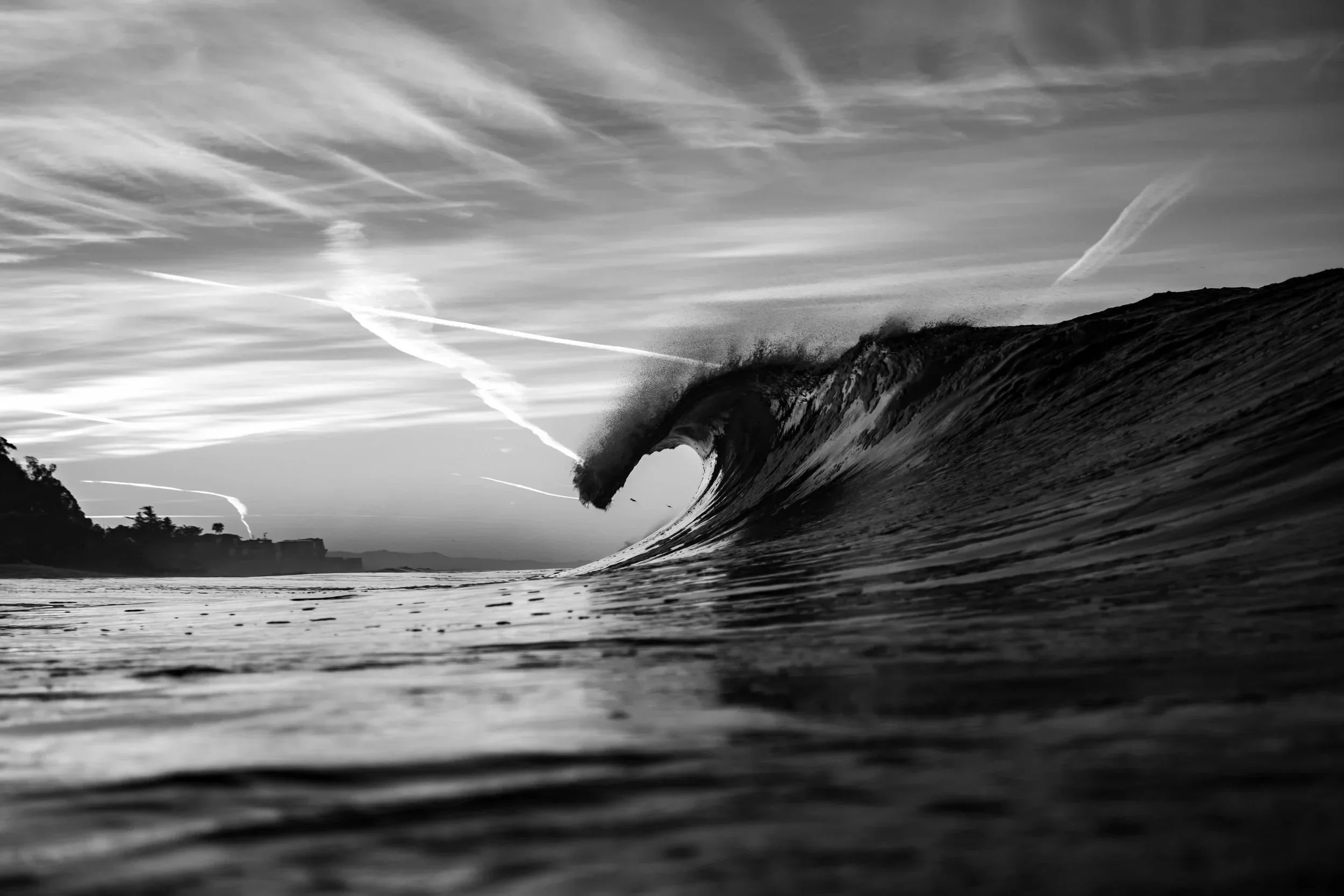 Breaking ocean wave approaching the shoreline under a dramatic sky