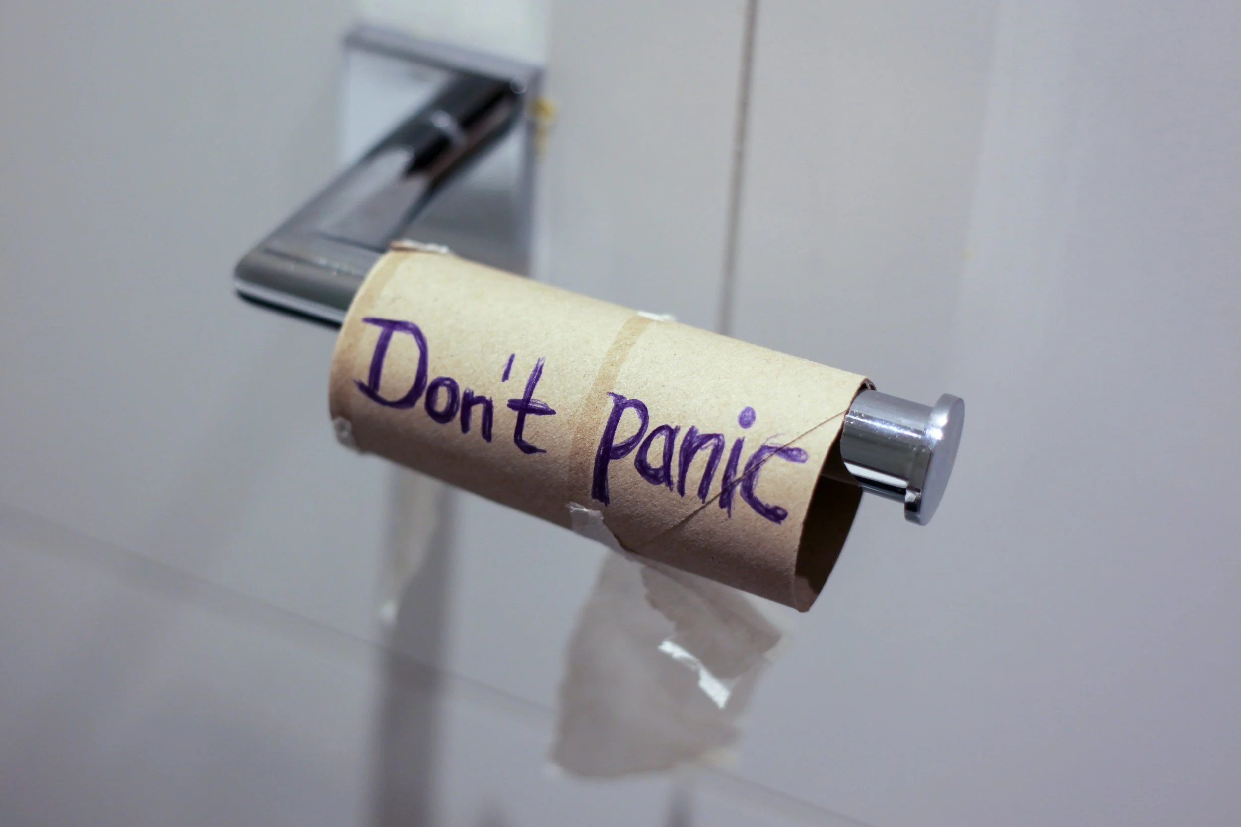 A toilet paper roll with a handwritten note saying 'Don't panic' in purple ink.