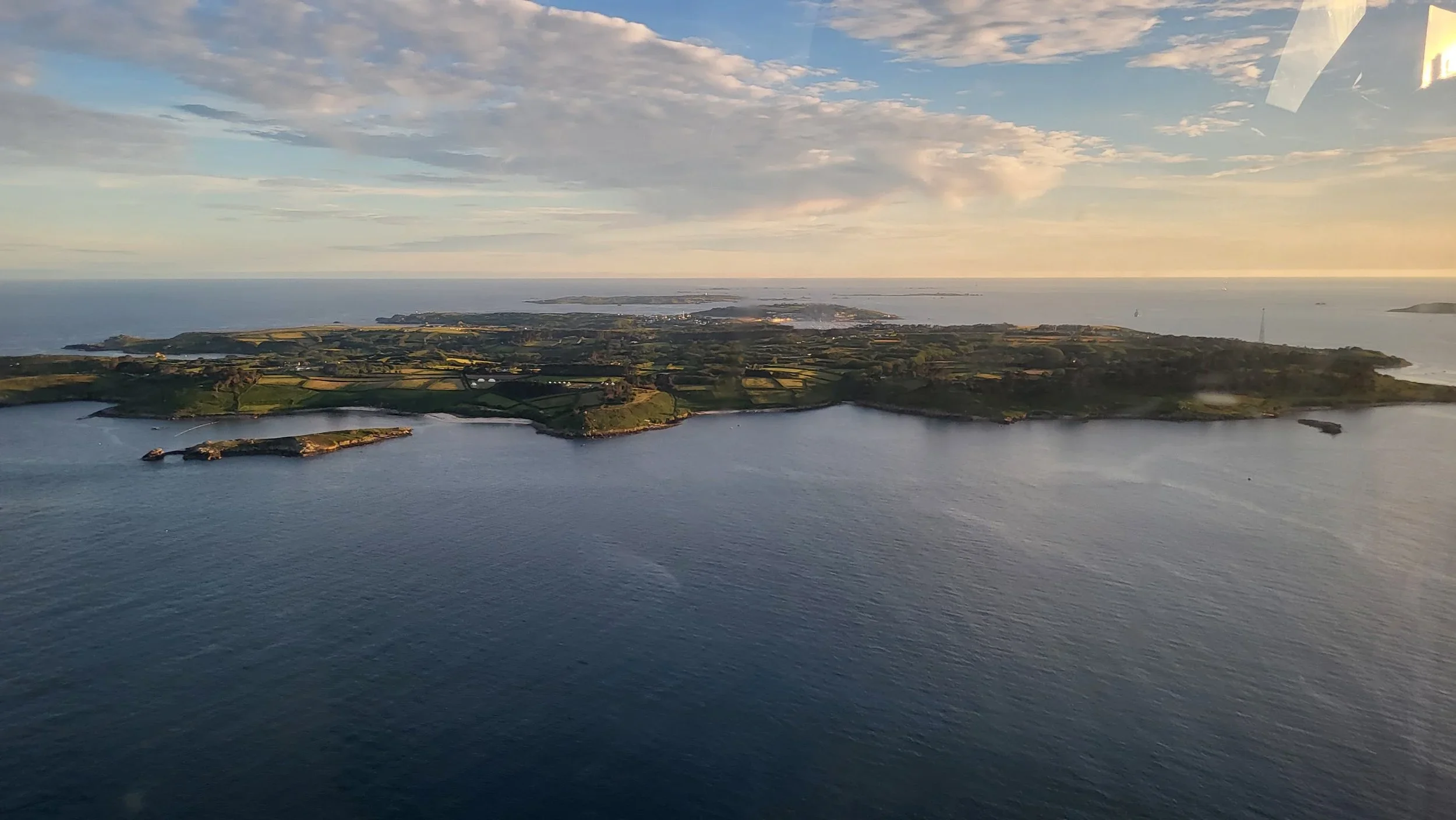Aerial view of an island under a partly cloudy sky near sunset.