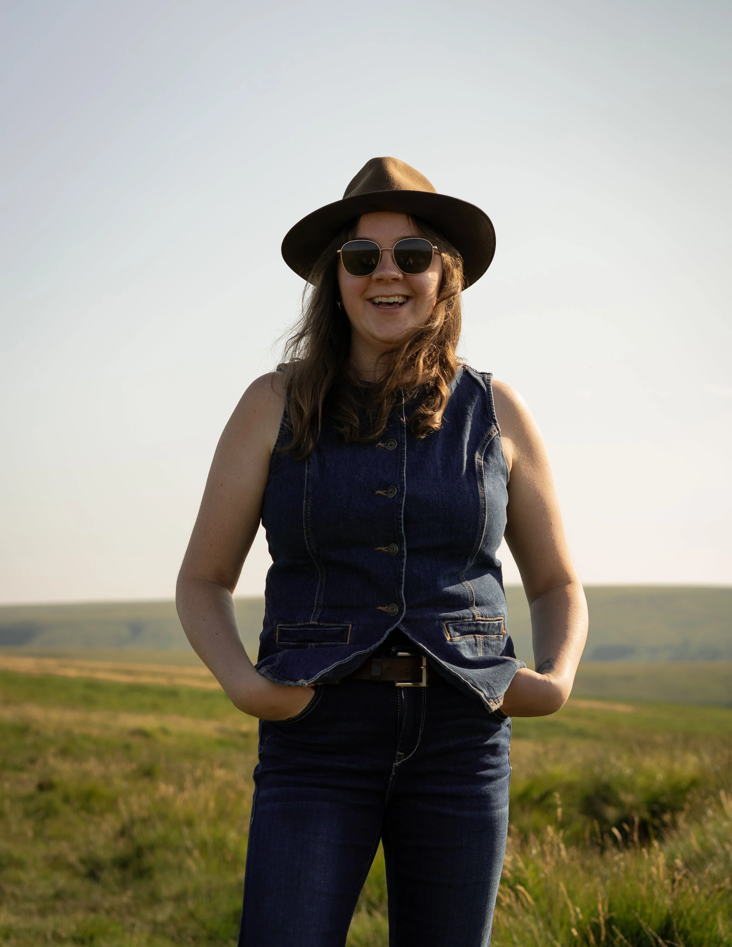 woman in all denim outfit, hat and sunglasses on smiling at the camera