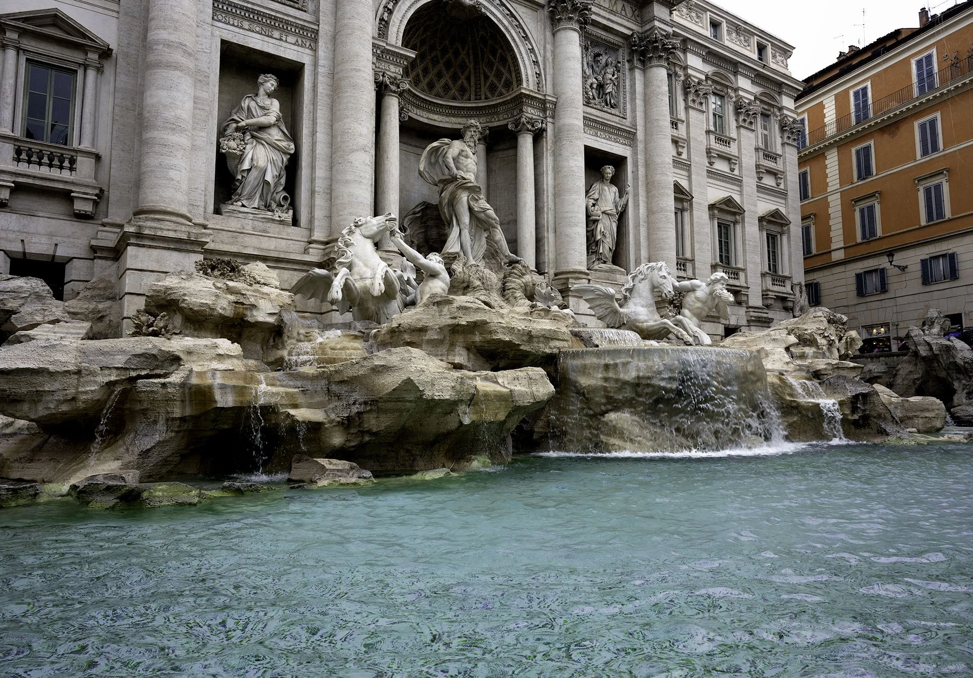 The Trevi Fountain in Rome, Italy, featuring intricate sculptures of mythological figures and cascading water in a historic Baroque style.