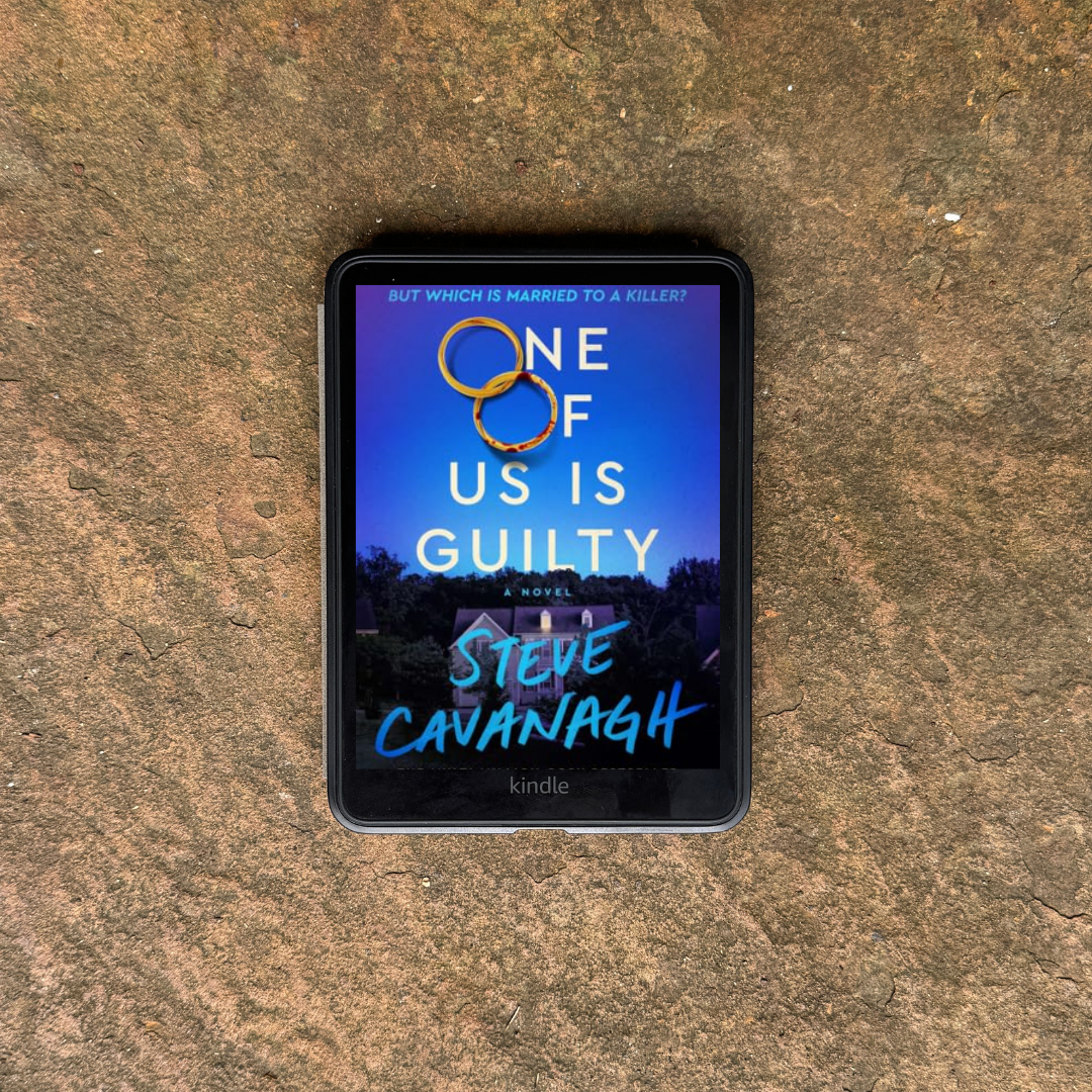 E-reader displays the book One of Us Is Guilty by Steve Cavanagh, resting on a large rock slab in warm earth tones.