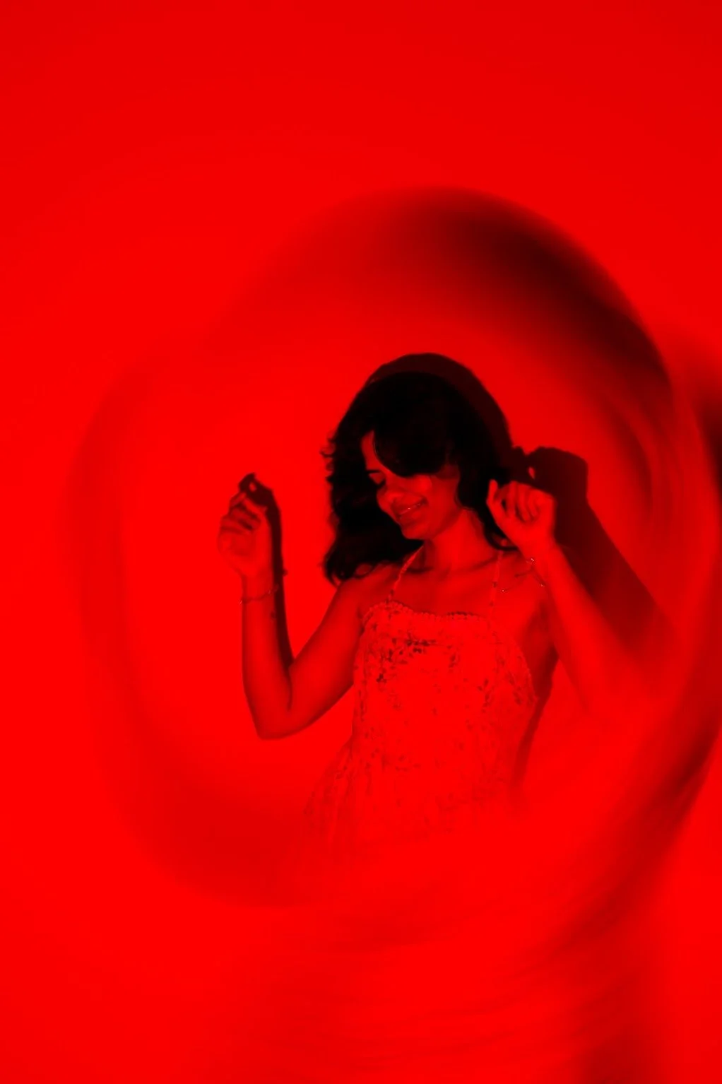 A woman dancing and smiling, surrounded by a red, swirling background.