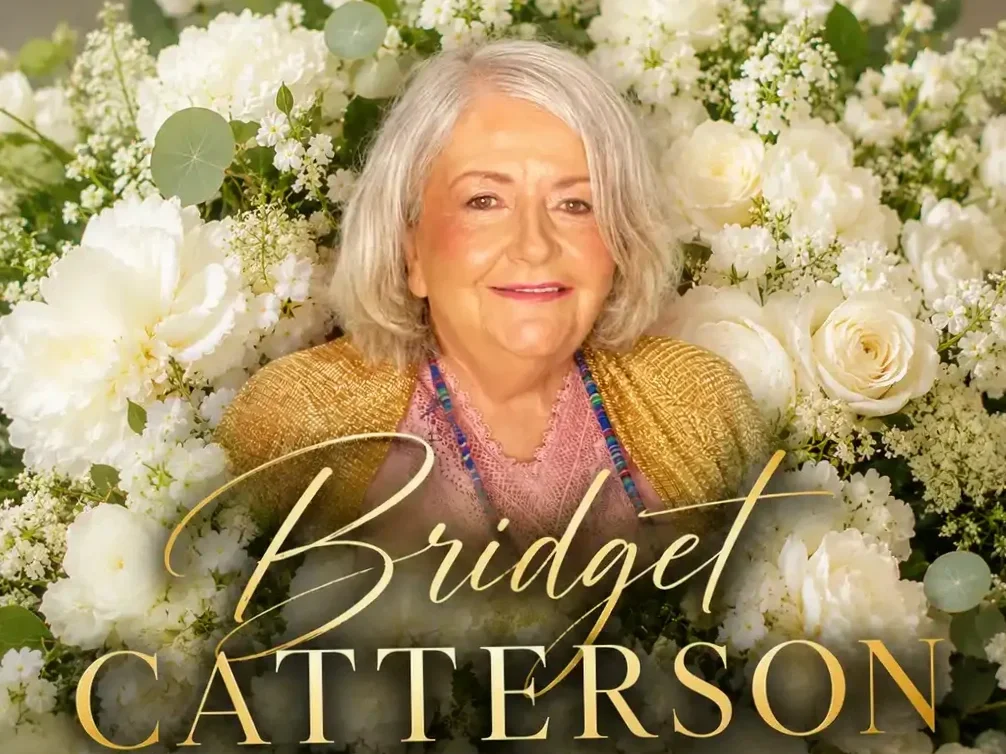 Portrait of a woman smiling, surrounded by a background of white flowers, and the text 'Bridget Catterson' in gold and white cursive font. Professional Celebrant
