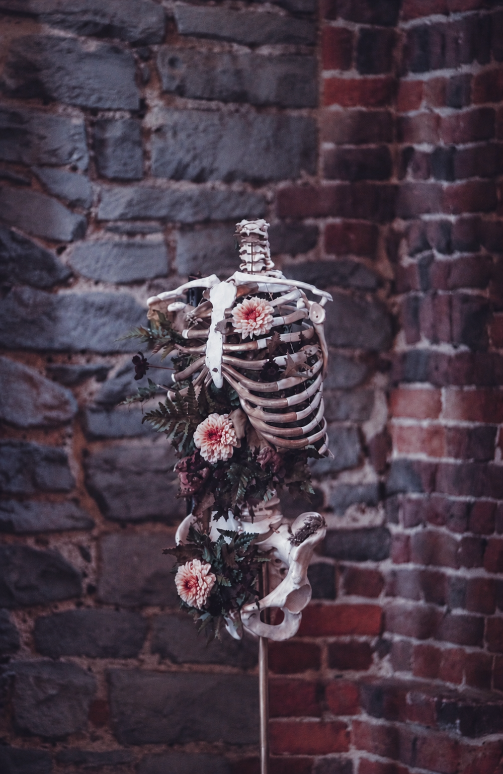 Squelette humain décoré de fleurs fraiches, pour une scénographie florale sombre et poétique.