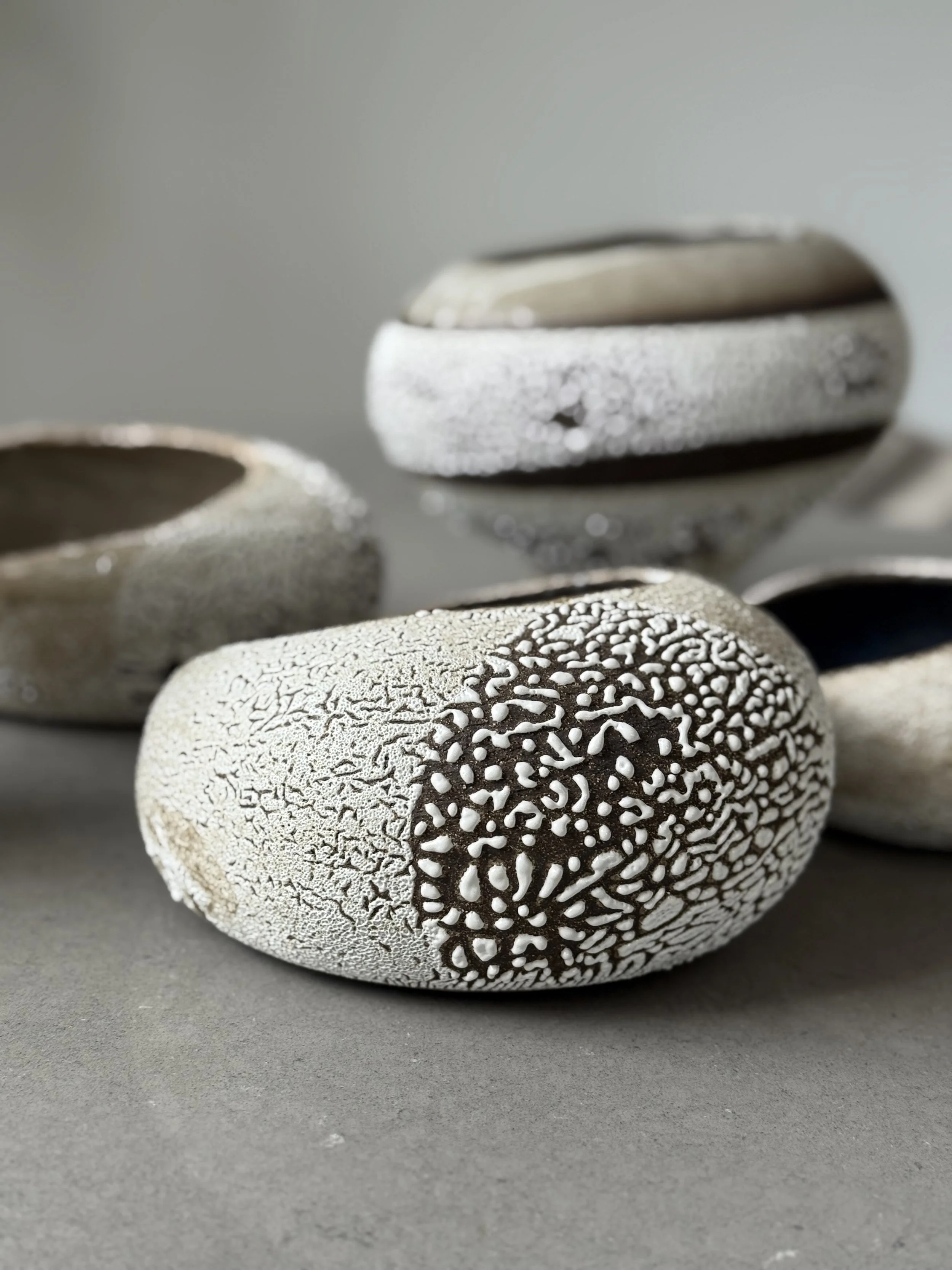 Close-up photo of decorative stones with textured, cracked, and patterned surfaces on a plain background.
