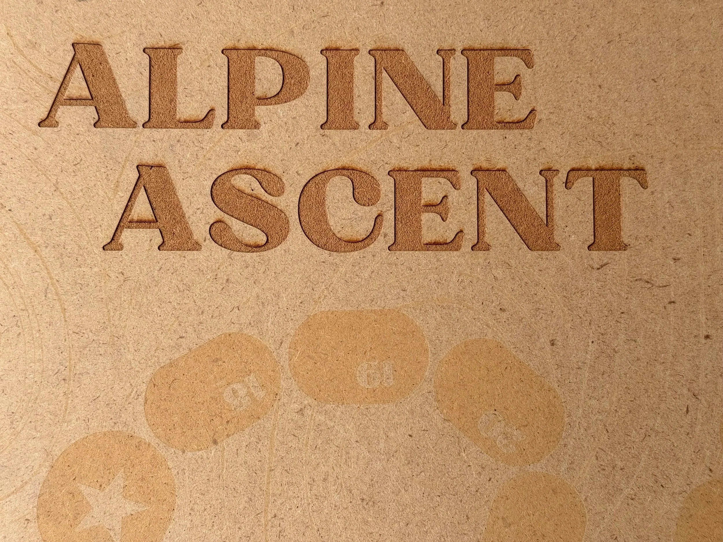 Close-up of embossed lettering on a textured surface, reading "ALPINE ASCENT" with large, bold, engraved letters.