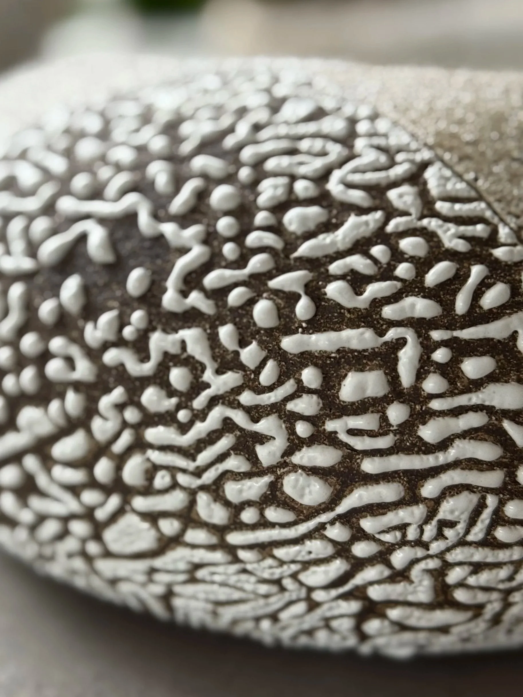 Close-up of a metal surface with white textured paint sprays on black surface, viewed through a circular opening.
