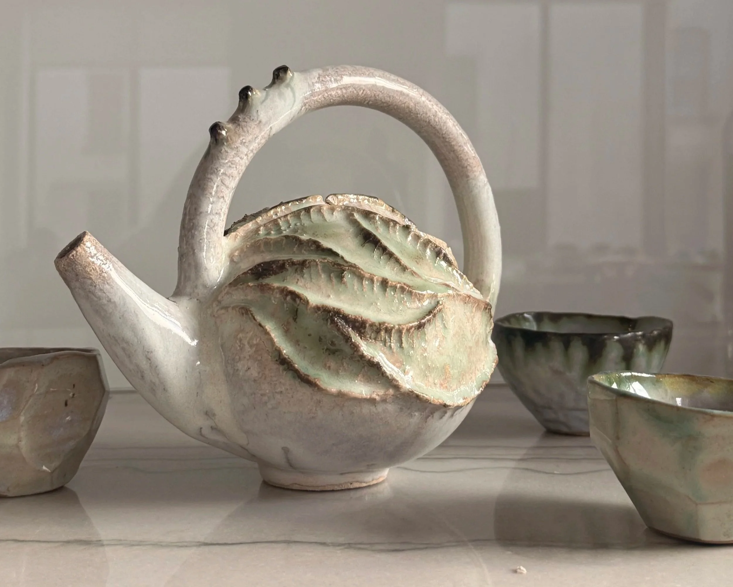 A ceramic sculpture of a whale with a fish on its back, displayed among other ceramic items.
