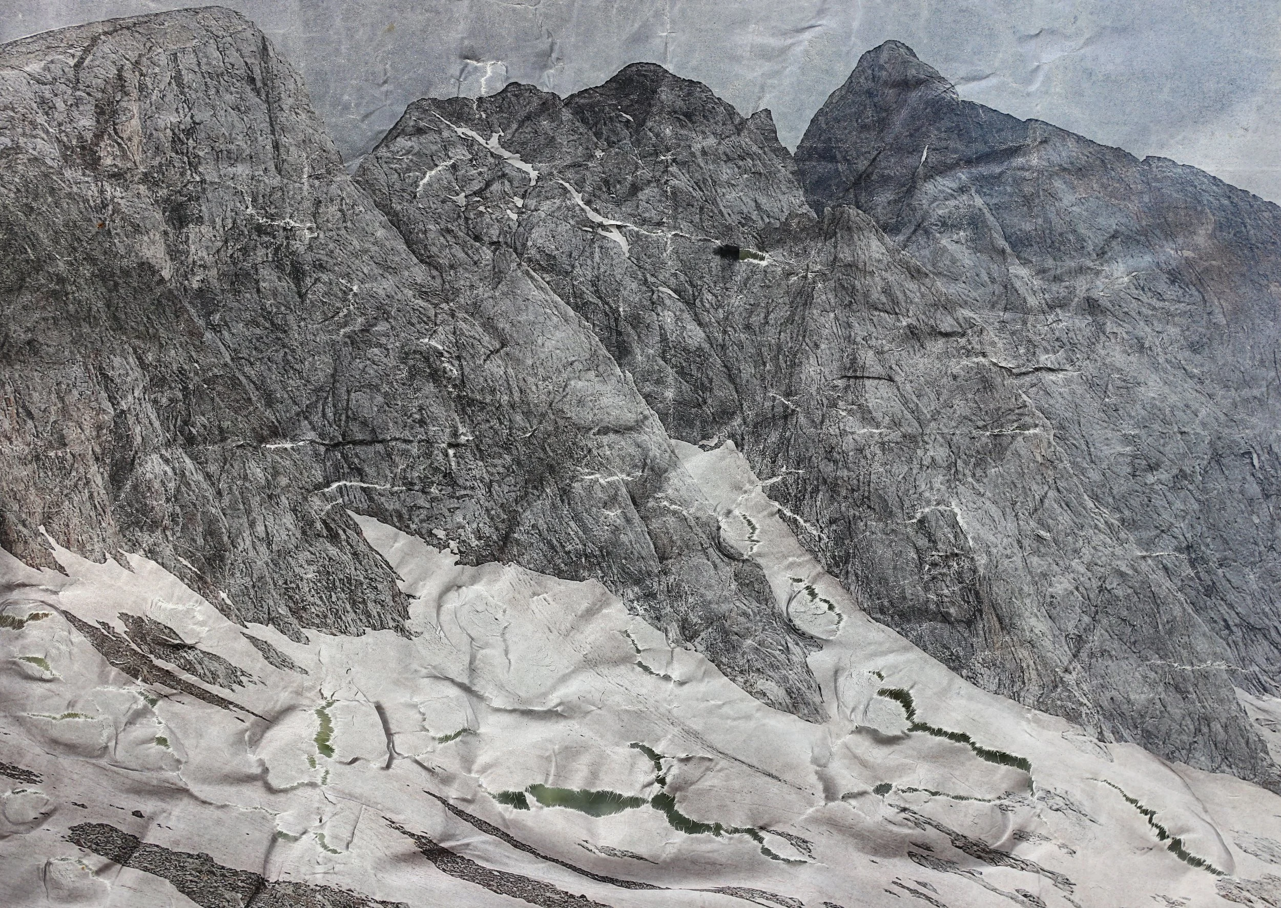 A rugged mountain landscape with rocky, snow-capped peaks and steep slopes.