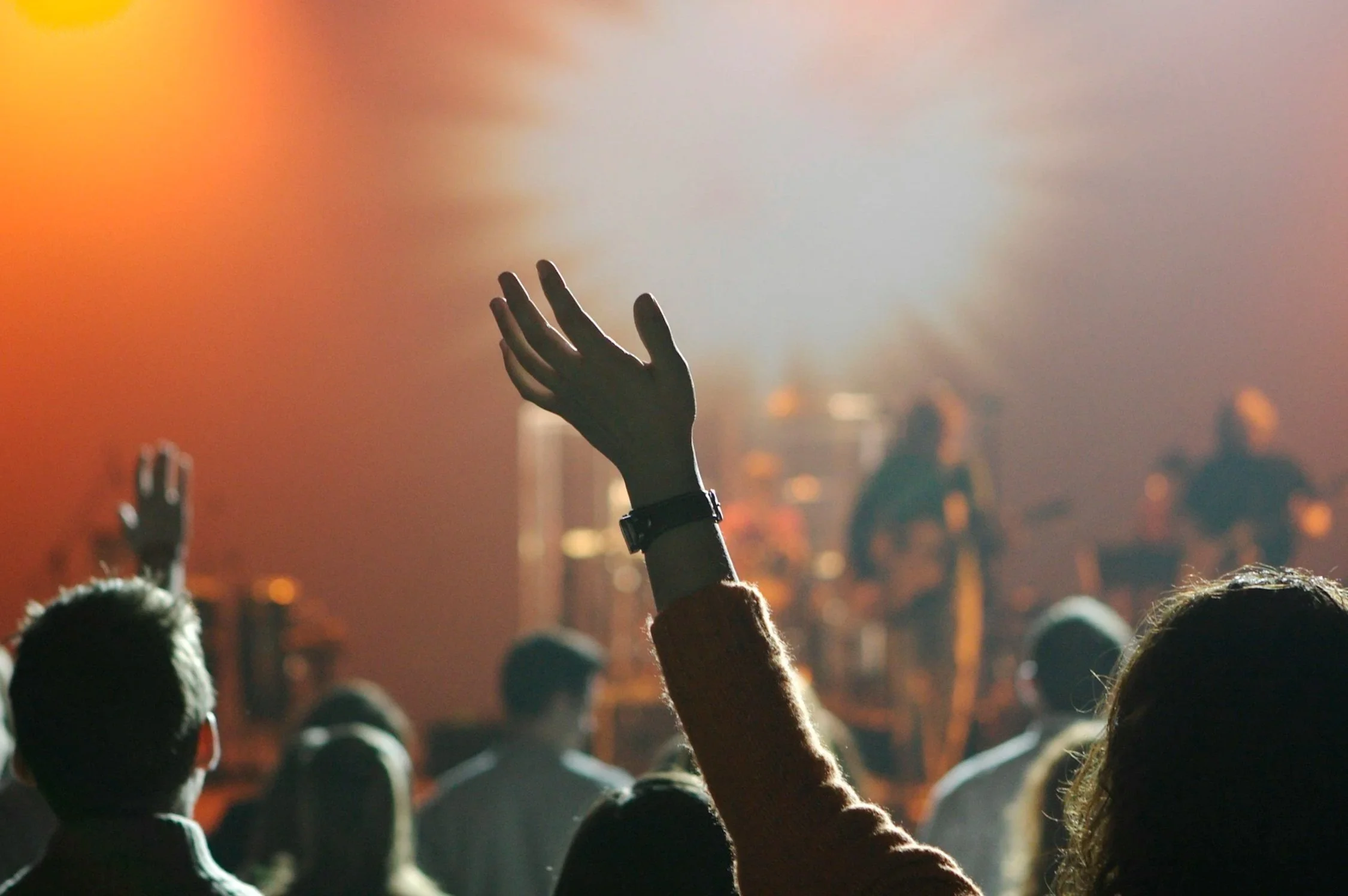 Crowd at a Christian church praising God, with a raised hand in the foreground