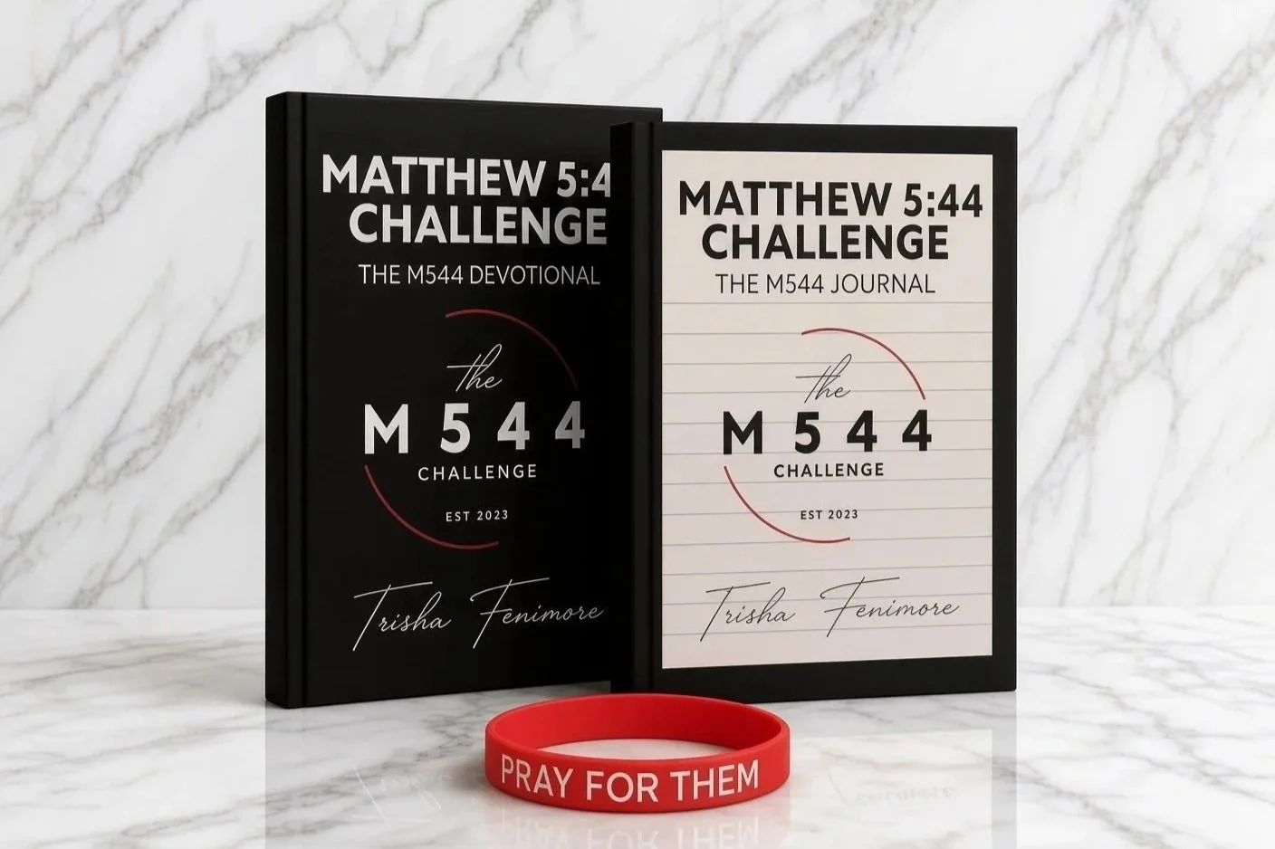 Two books titled 'Matthew 5:44 Challenge' and 'Matthew 5:44 Challenge The M544 Journal' by Trisha Fenimore are displayed on a white marble surface, with a red wristband that says 'Pray for Them' in front of them, against a white marble background.