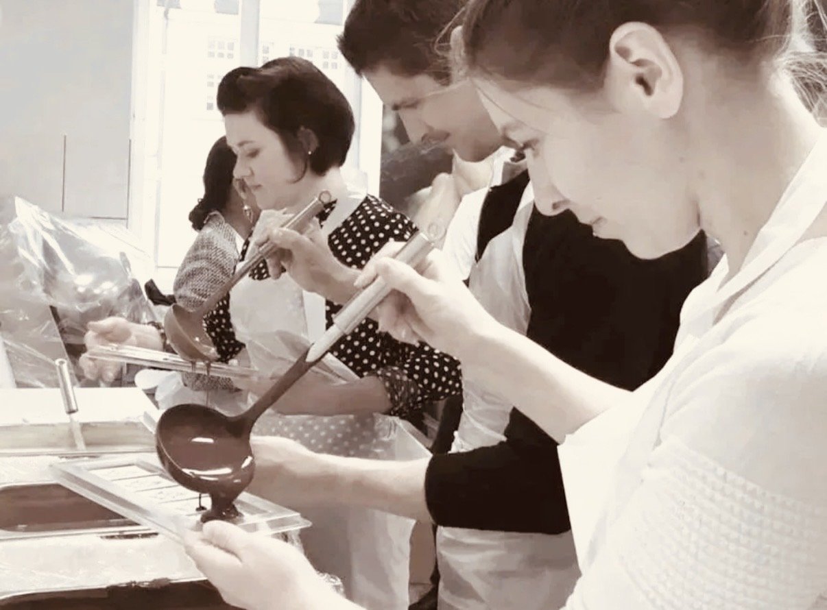 Menschen beim Schokoladentafel giessen Workshop, die mit Schokoladen-Temperatur und -Textur arbeiten.