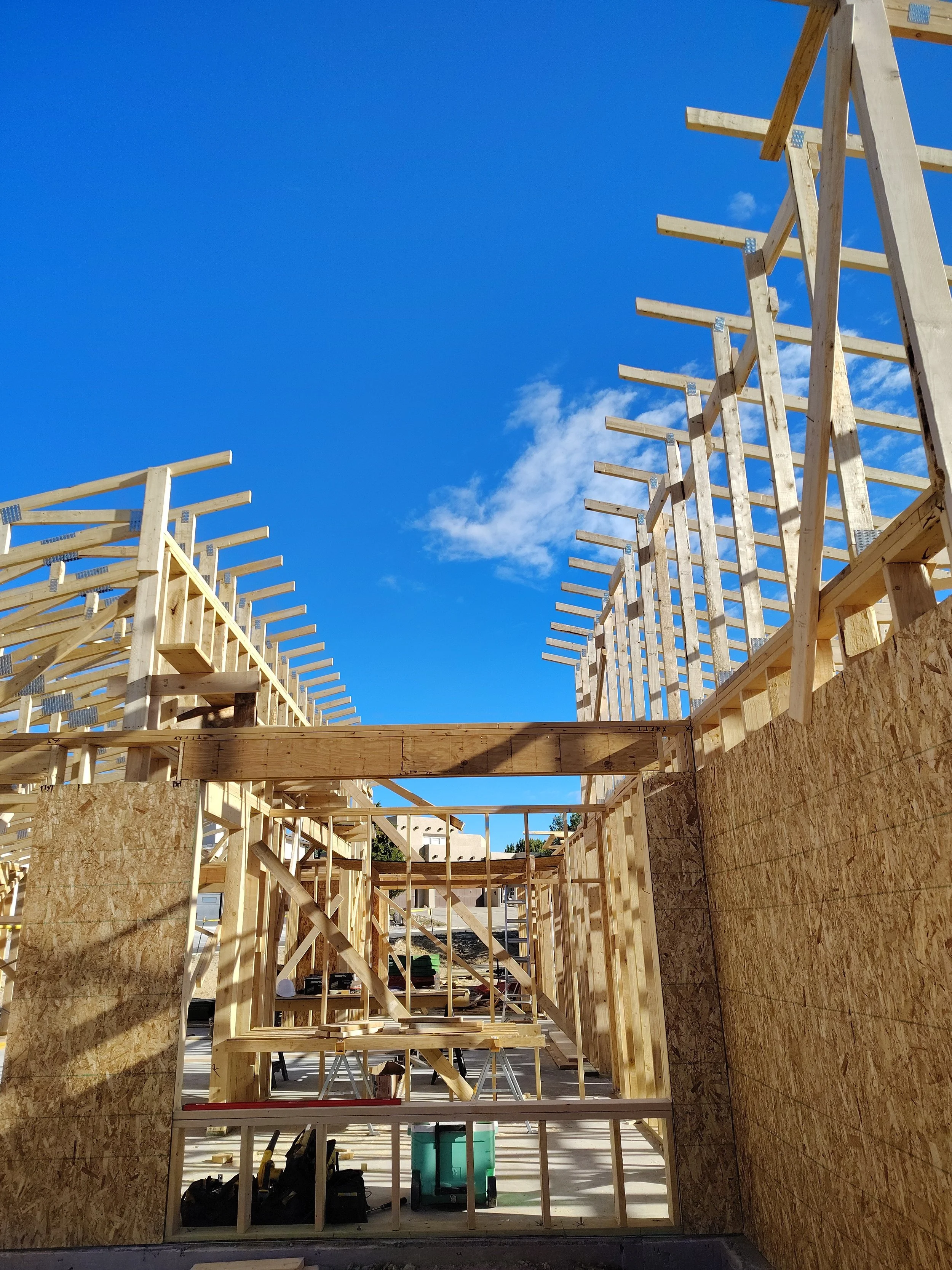 Wood framing under construction inside a building with blue sky visible through open walls.