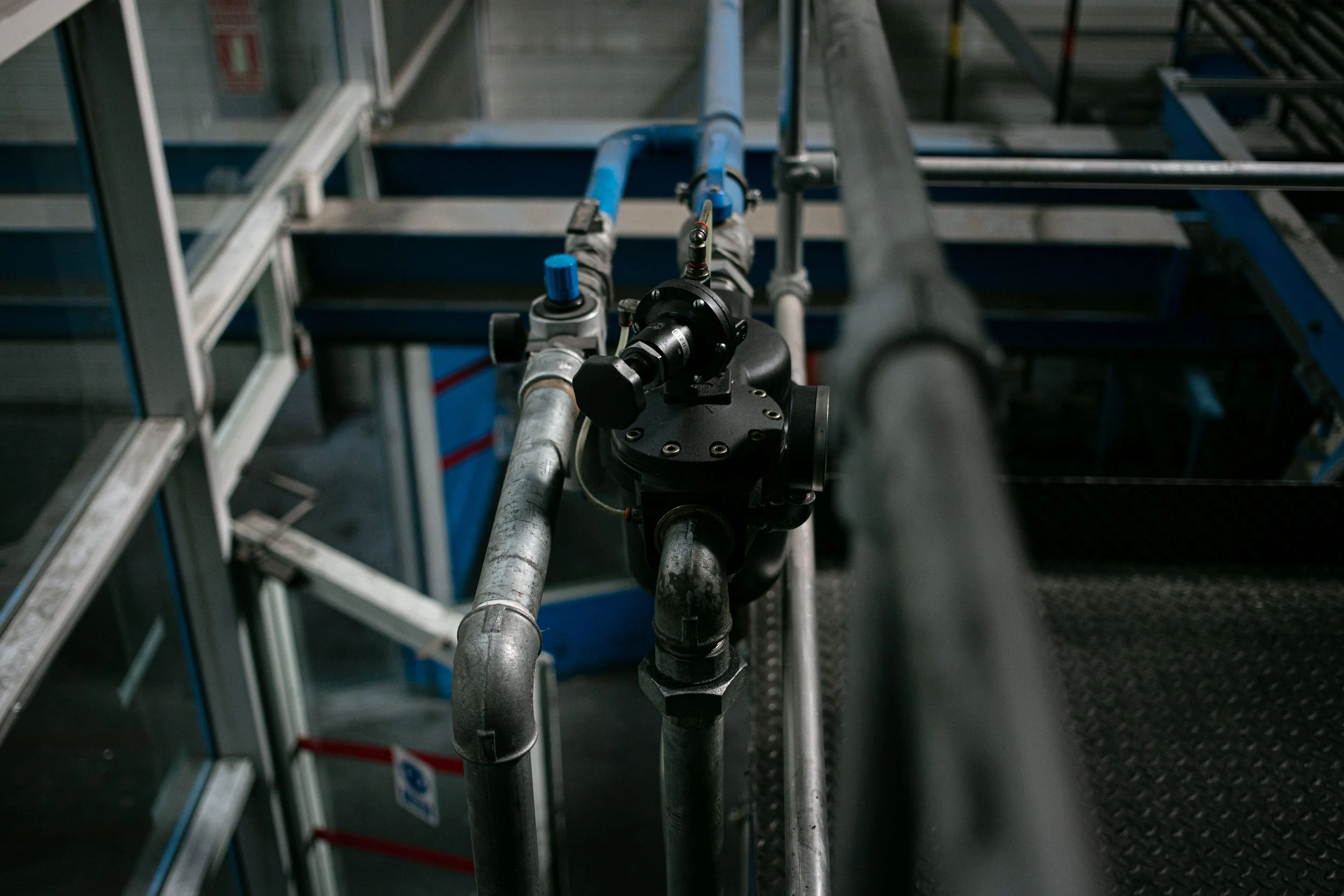 Impianto industriale con tubature e valve in primo piano, ambientazione di una fabbrica o centrale di distribuzione.
