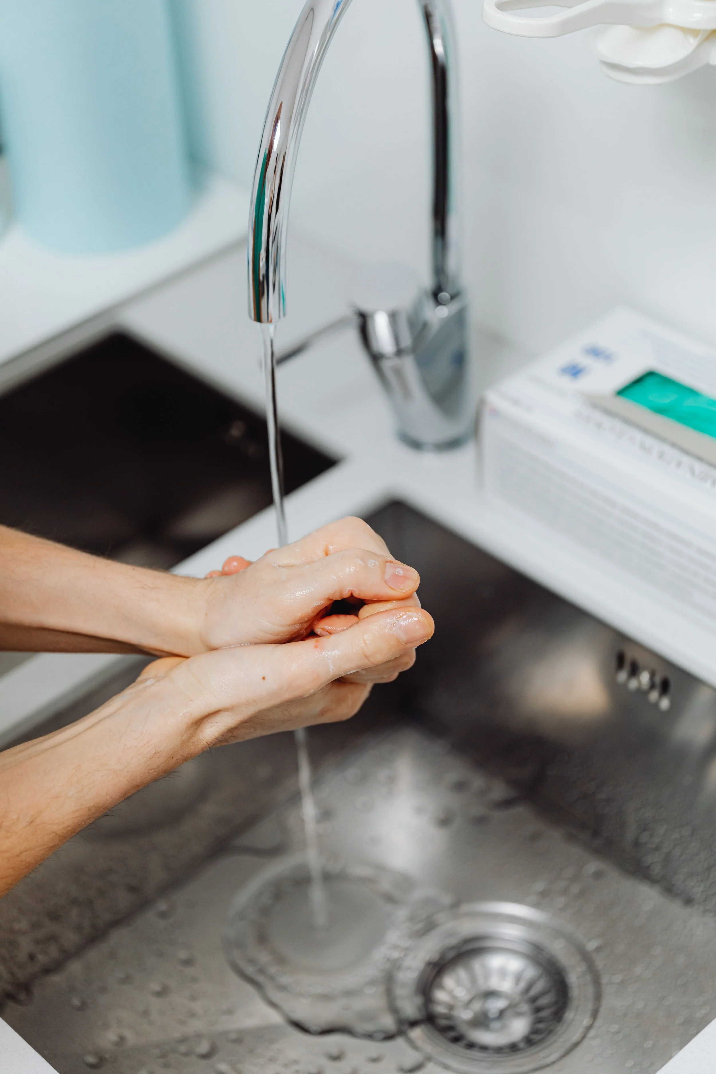 Una persona si lava le mani sotto il rubinetto dell'acqua calda in cucina.