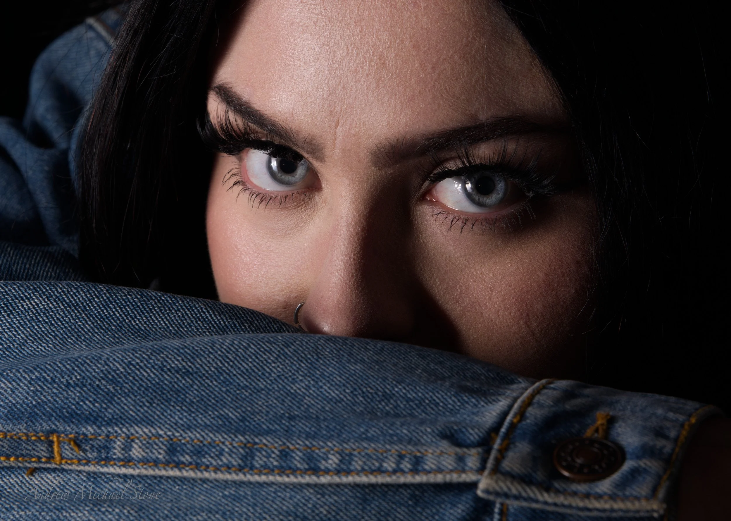 clops-up portrait of a woman resting her face on a denim jacket sleeve, focusing on eyes [andrew Michael stone photography/Devonsire, UK]
