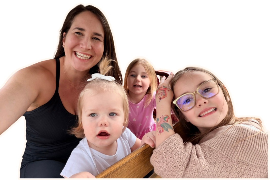 Four people, including a woman and three children, smiling and posing together indoors.