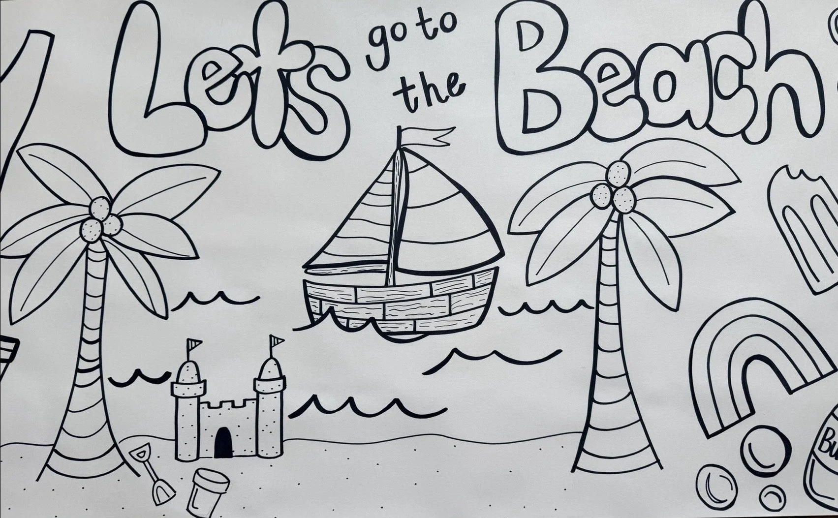 Black and white drawing of a beach scene with palm trees, a sandcastle, a sailboat, rainbows, and the text "Let's go to the beach."