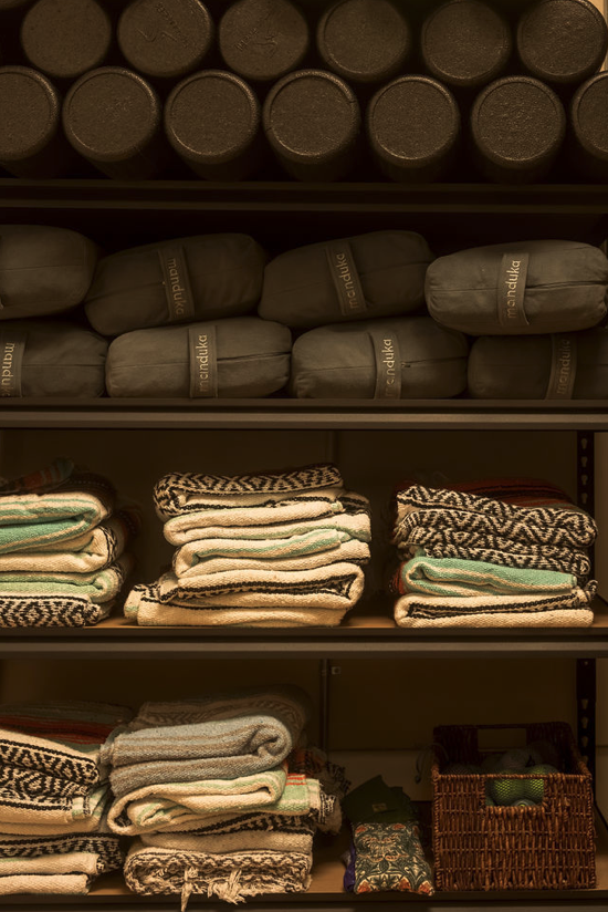 Shelves with rolled towels, folded blankets, and a basket of tennis balls.
