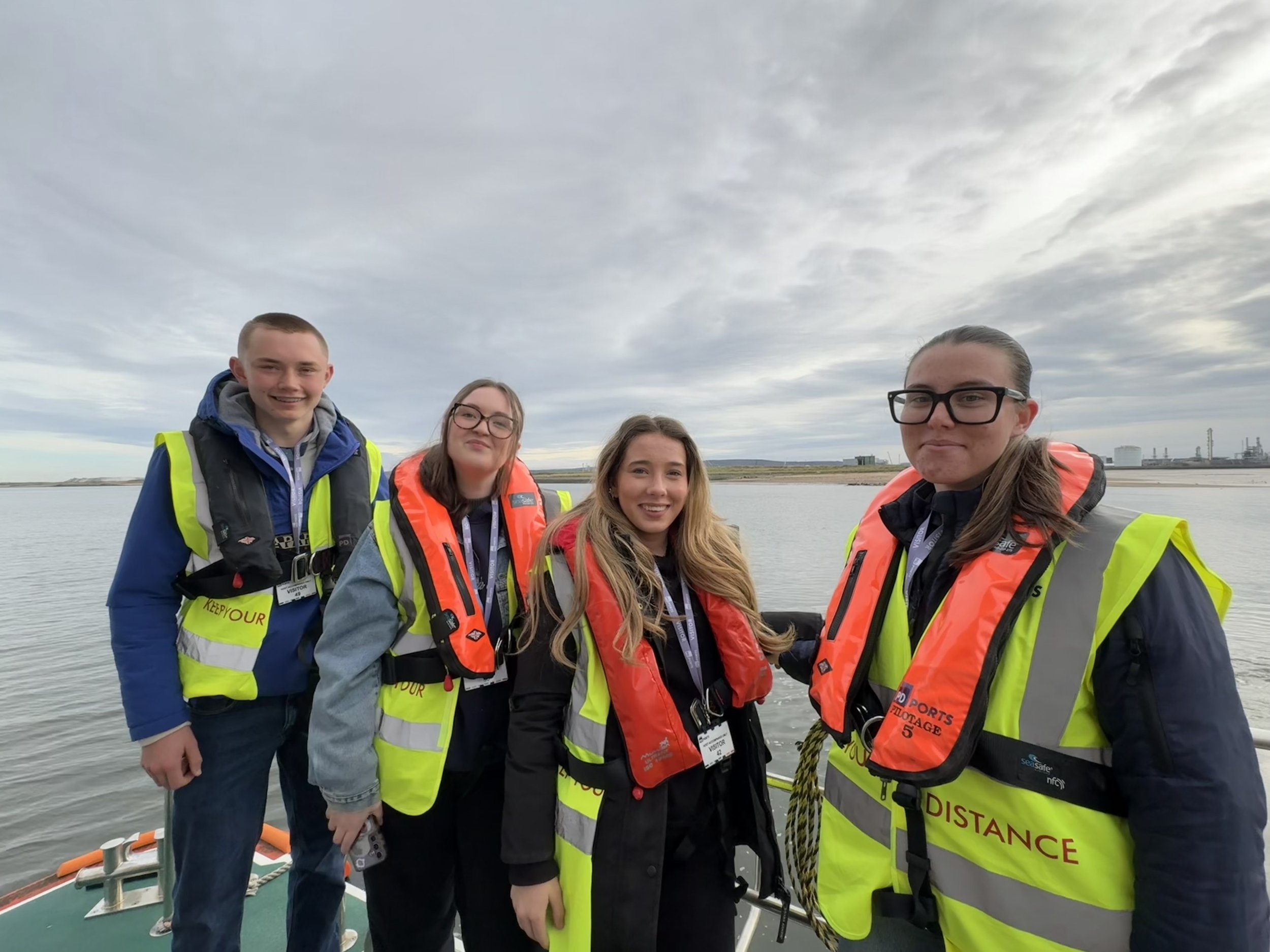Four members of the Tees Maritime Youth Board wearing safety equipment during a boat trip on the River Tees.