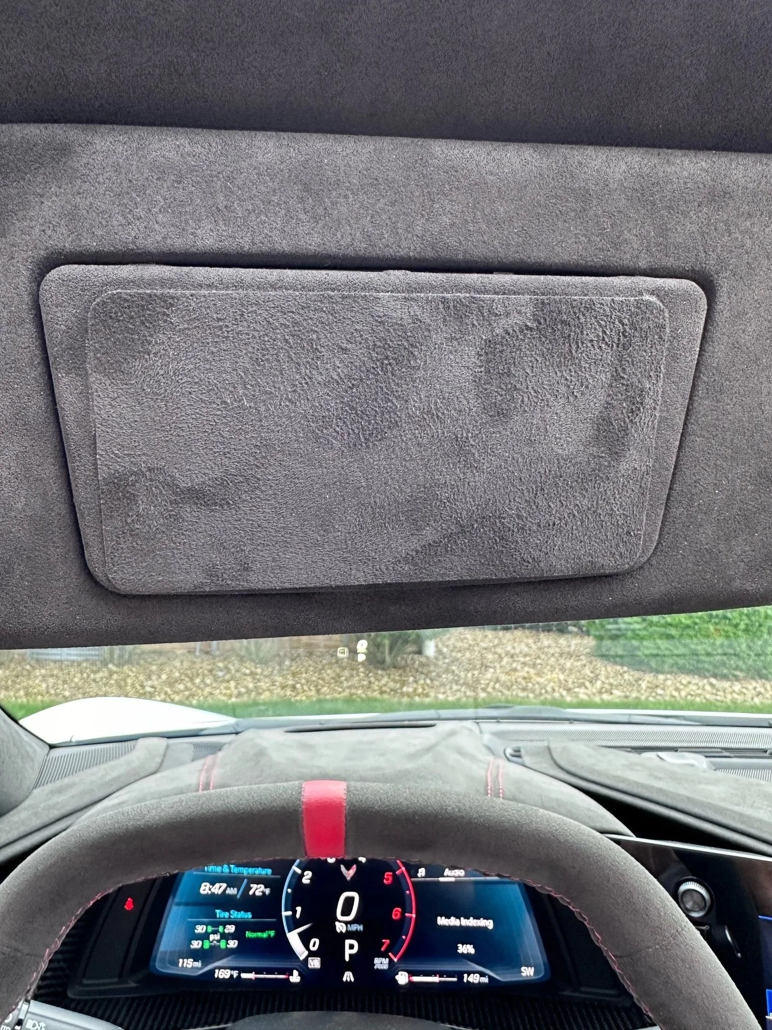 Driver’s view through a car windshield with dashboard, steering wheel, and sun visor visible.