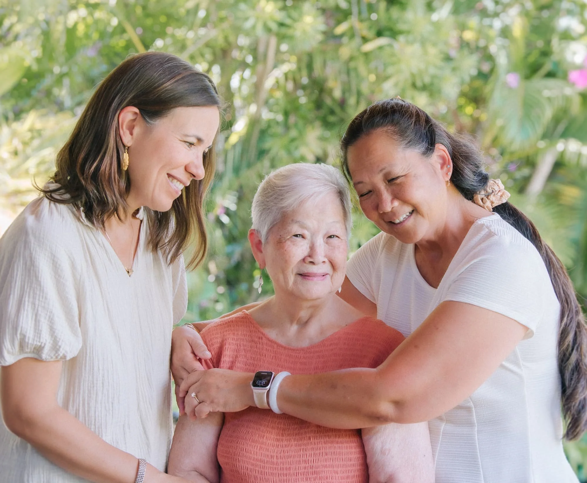 Nurse practitioner sharing a warm embrace with a senior patient and her daughter during an in-home visit