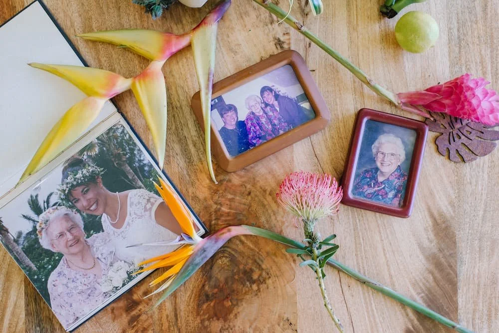 Old family photographs of Lani Hubbard and her grandmother displayed with tropical flowers on a wooden table