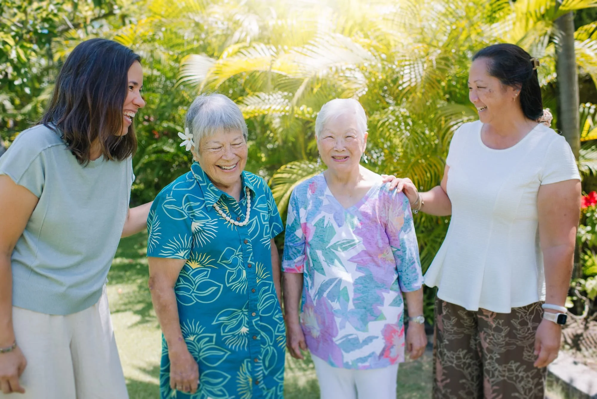 Nurse practitioner laughing together with two senior patients and a family caregiver in a garden setting