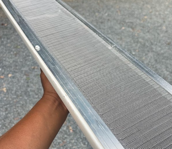 Close-up of a person holding a metal air filter with a gray textured background.